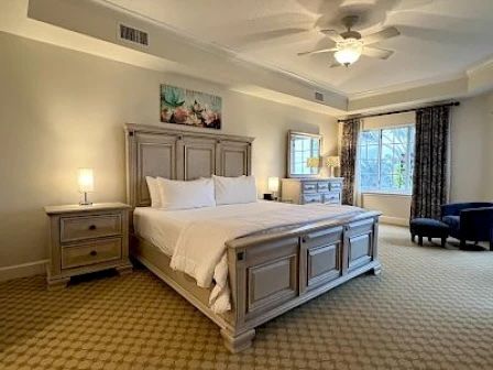 image King master bedroom with soft white linens, natural light, and warm coastal tones