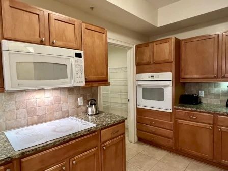 image Kitchen with warm wood cabinetry, granite counters, and a two-seat kitchen bar