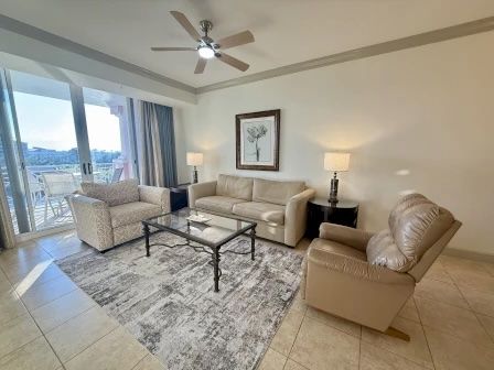 image Sunlit living area with plush sectional seating and open views to the waterway outside