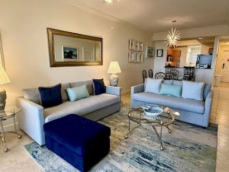 image Living area with plush seating, a round coffee table, and open flow to the kitchen and balcony