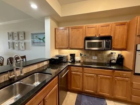image Kitchen with warm wood cabinetry, dark stone counters, and full-sized appliances