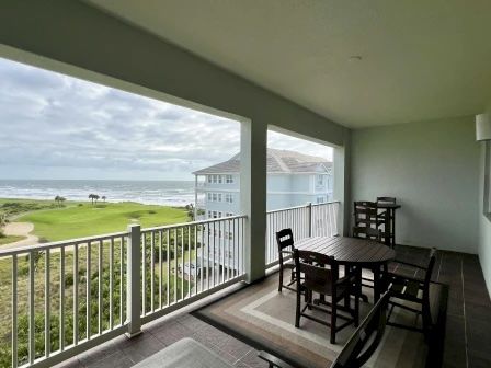 image Private balcony with seating overlooking ocean waves and lush golf course greens below