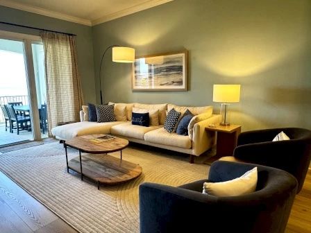 image Living area with plush sectional, natural light, and open flow to the kitchen and balcony
