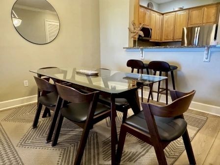 image Glass dining table with six seats beneath a warm pendant light