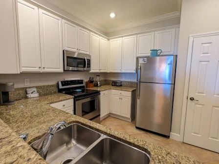 image Bright kitchen with stainless appliances, granite counters, and a three-seat kitchen bar