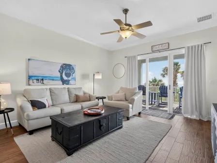 image Living area with light-toned sofas, warm wood accents, and balcony access with ocean views