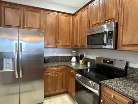 image Kitchen with rich wood cabinetry, granite counters, and full-sized appliances for group cooking