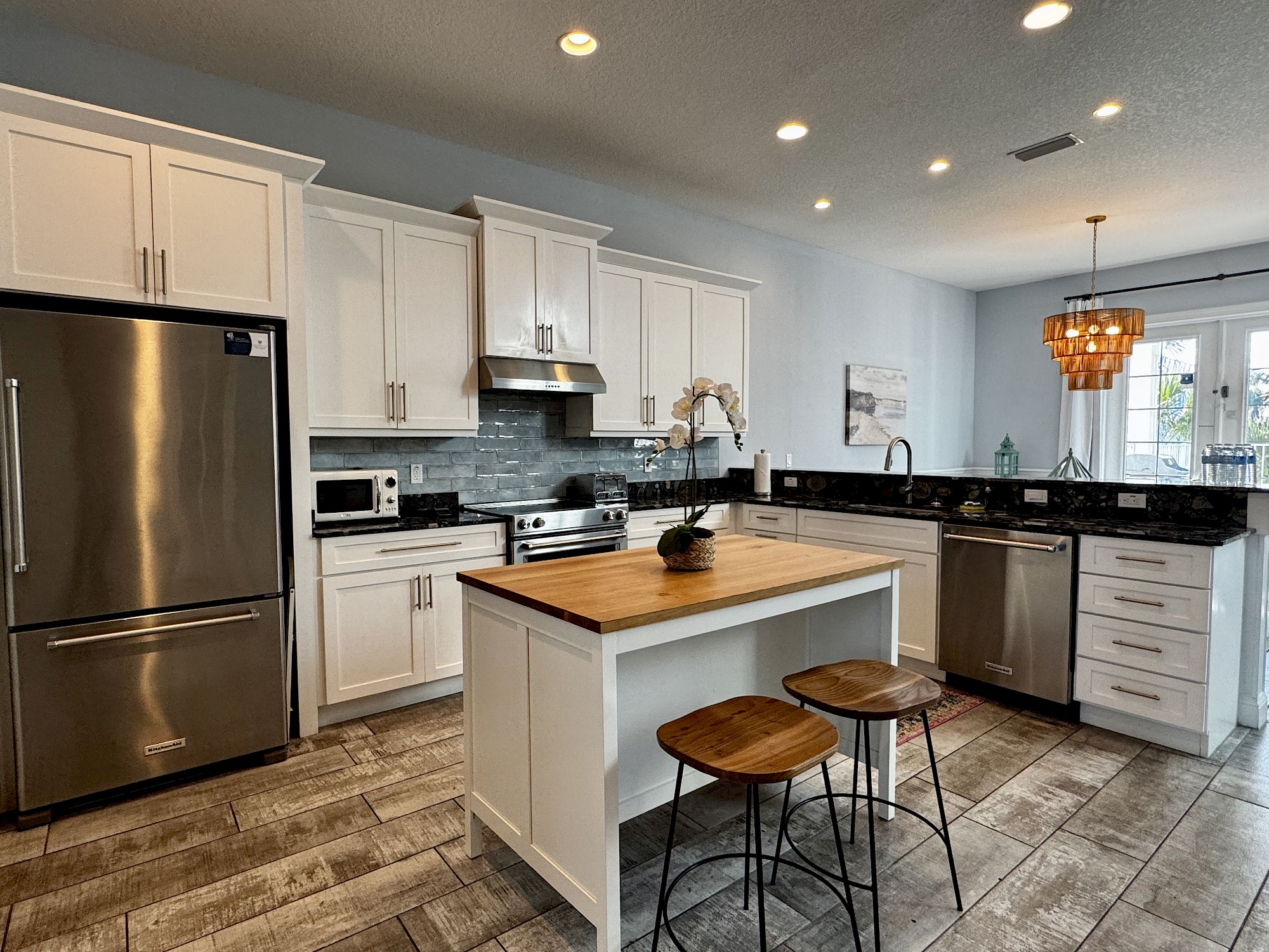 image Fully equipped kitchen with stainless steel appliances, kitchen bar, and blue tile accents