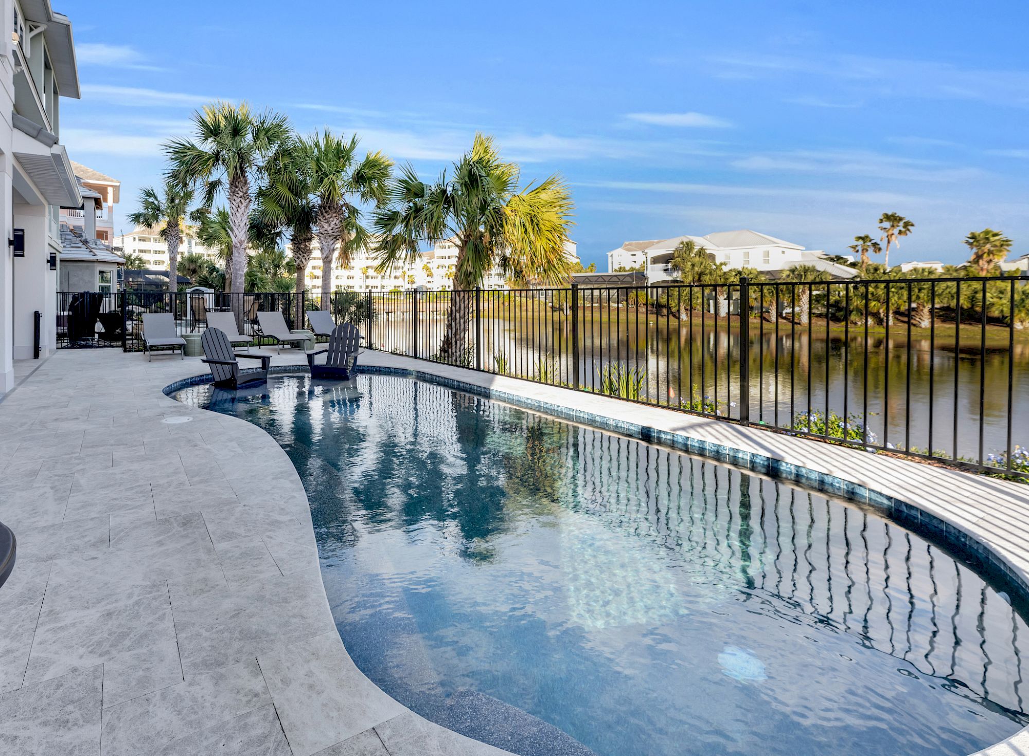 image Heated private pool with waterfront views and palm trees — the outdoor patio and grill sit just alongside