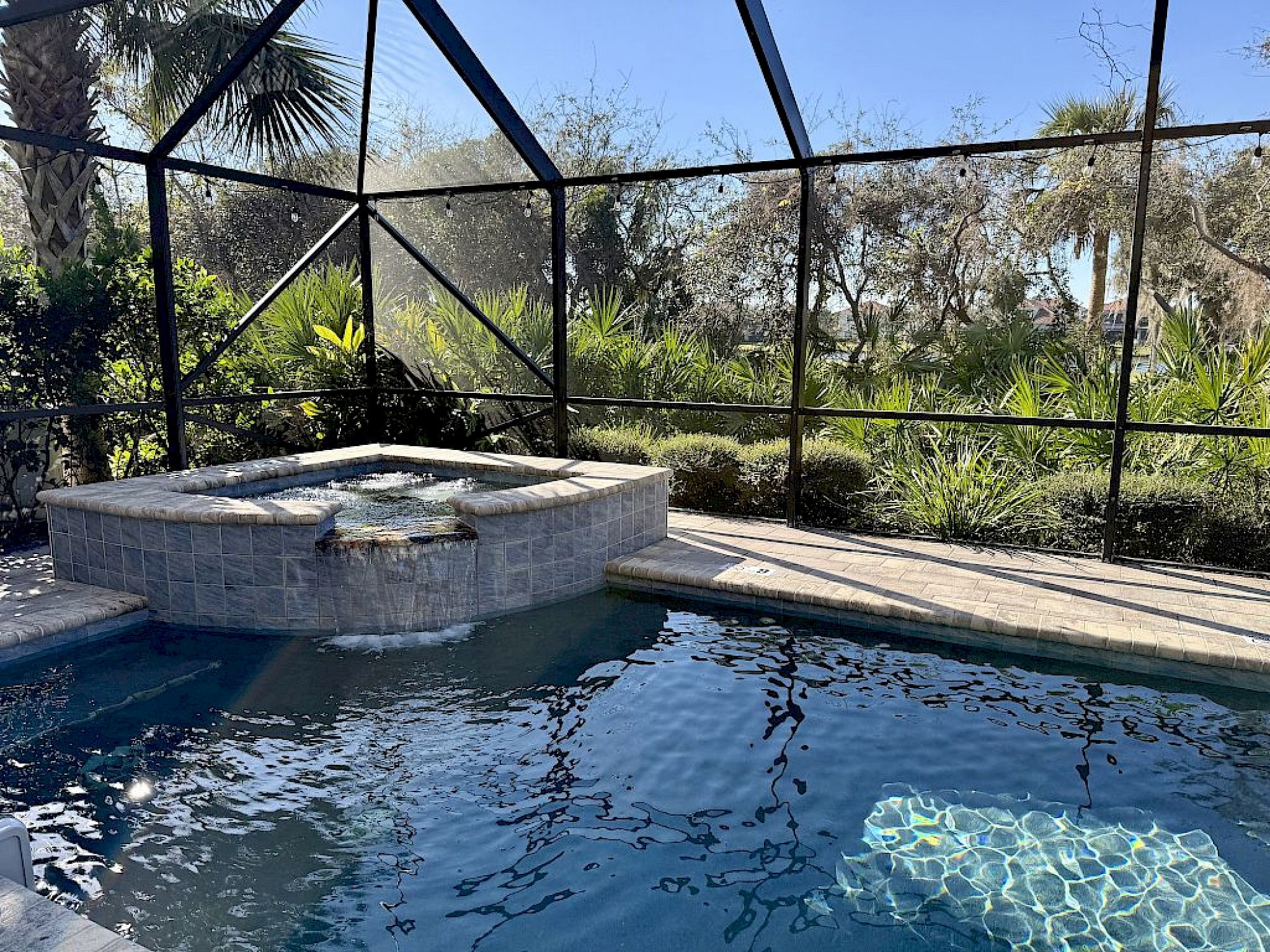 image Private heated pool and spa with lush greenery on all sides — golf course just beyond the fence