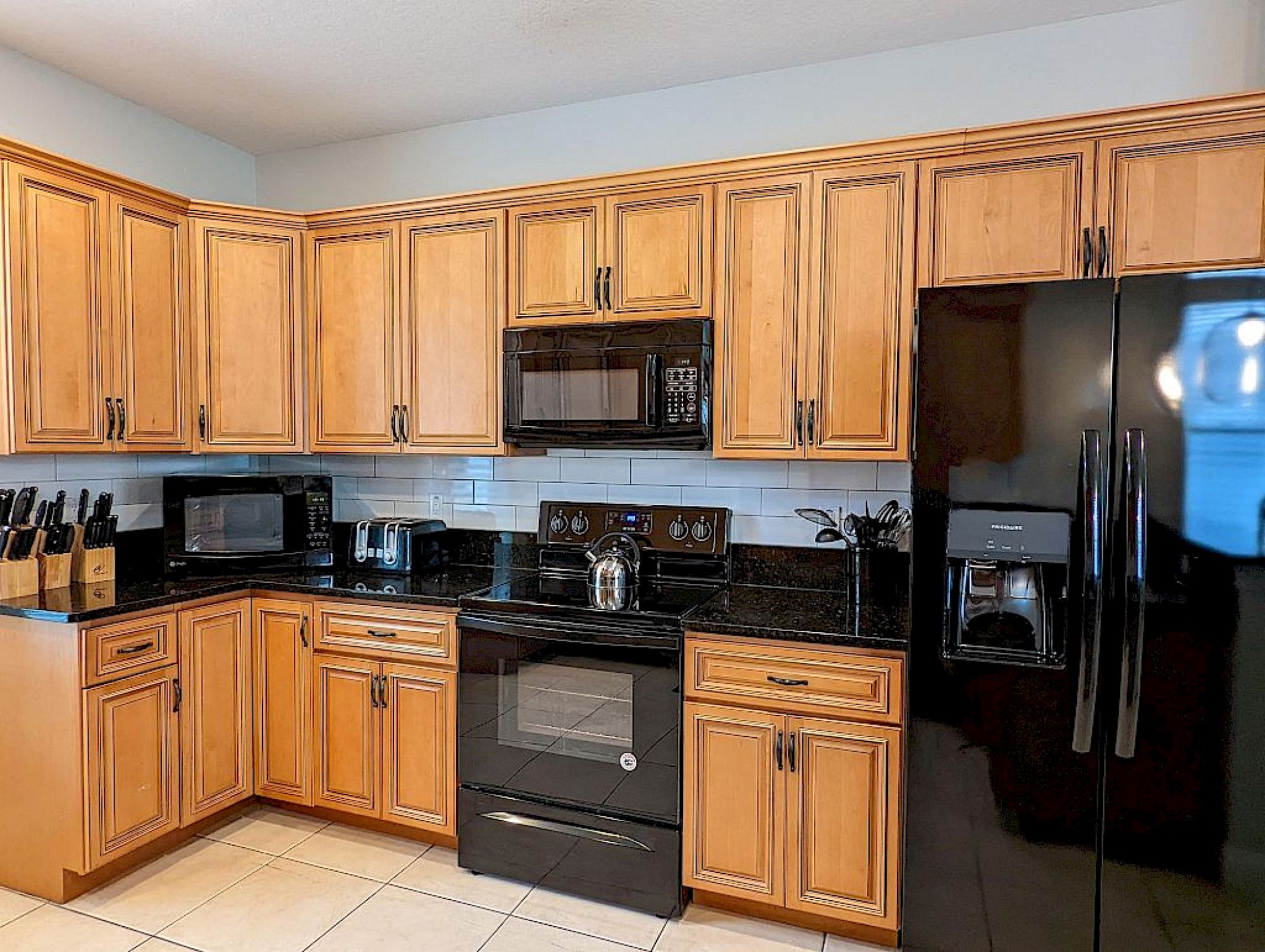 image Fully equipped kitchen with dark granite counters, rich wood cabinetry, and full-sized stainless appliances