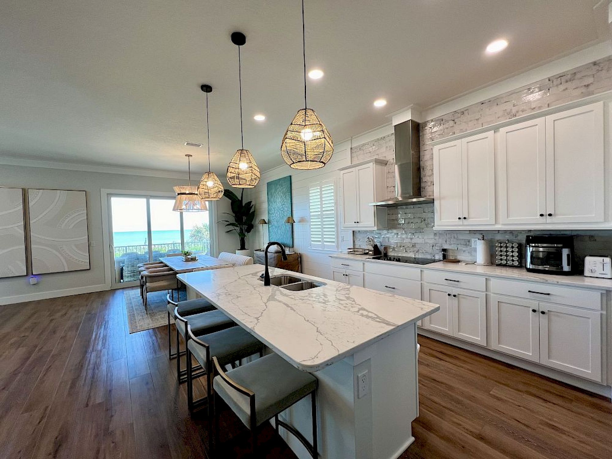 image Kitchen with marble-look island, kitchen bar seating, woven pendant lights, and full-sized appliances