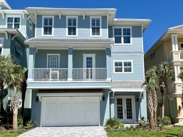 image Spacious multi-story home with a private garage, covered balconies, and charming palm-lined entrance