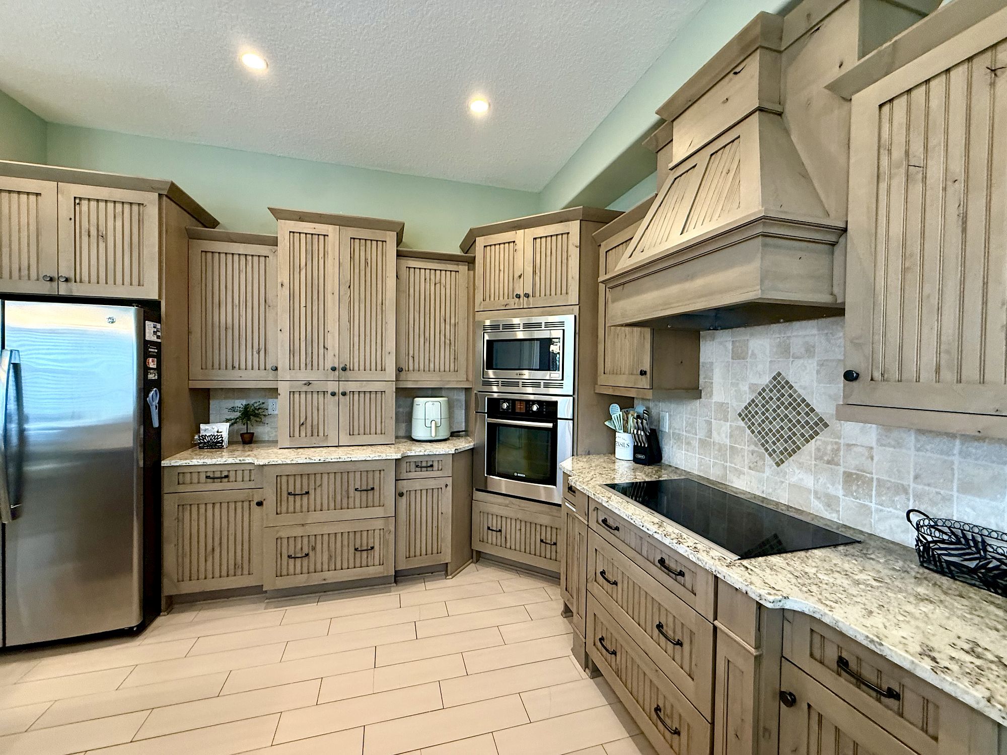 image Gourmet kitchen with beadboard cabinetry, granite counters, and full-sized modern appliances