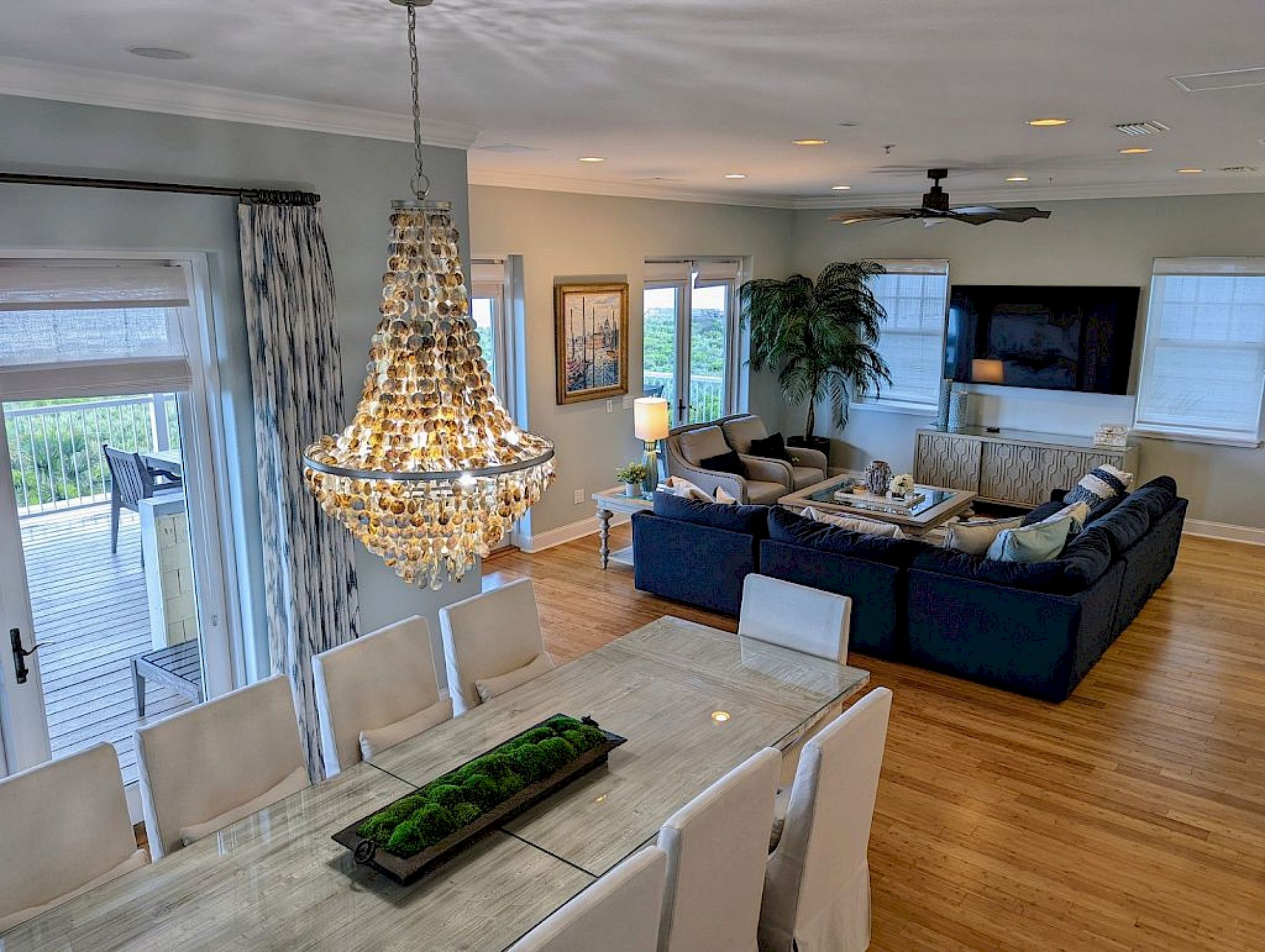 image Dining room with glass-top table, eight upholstered chairs, crystal chandelier, and large windows
