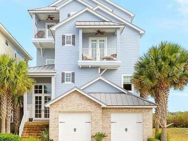 image Elegant coastal home with a welcoming entrance, covered balconies, and palm-lined surroundings