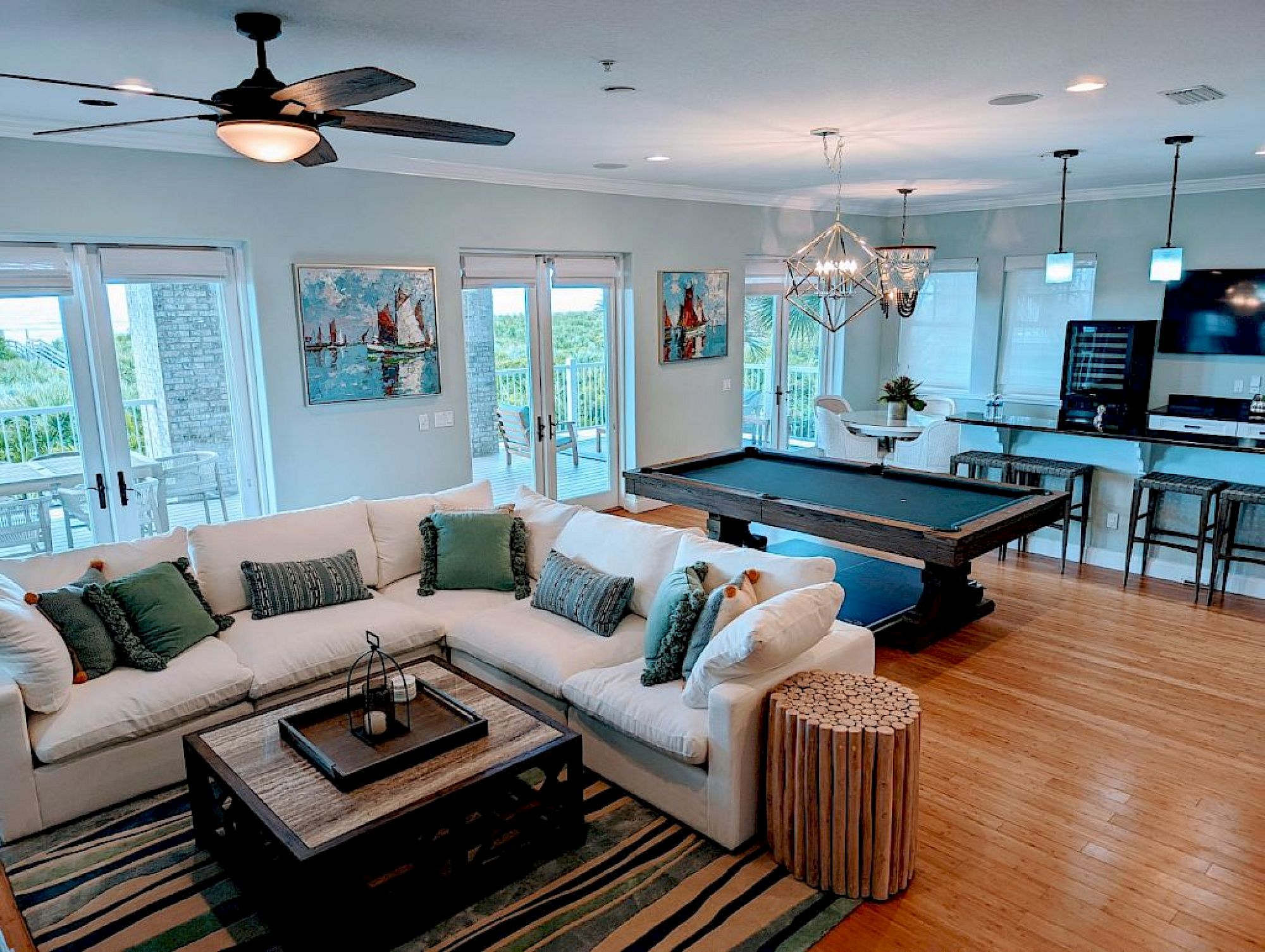 image Game room with pool table, bar with stools, pendant lights, and wall art — ocean views through the windows behind
