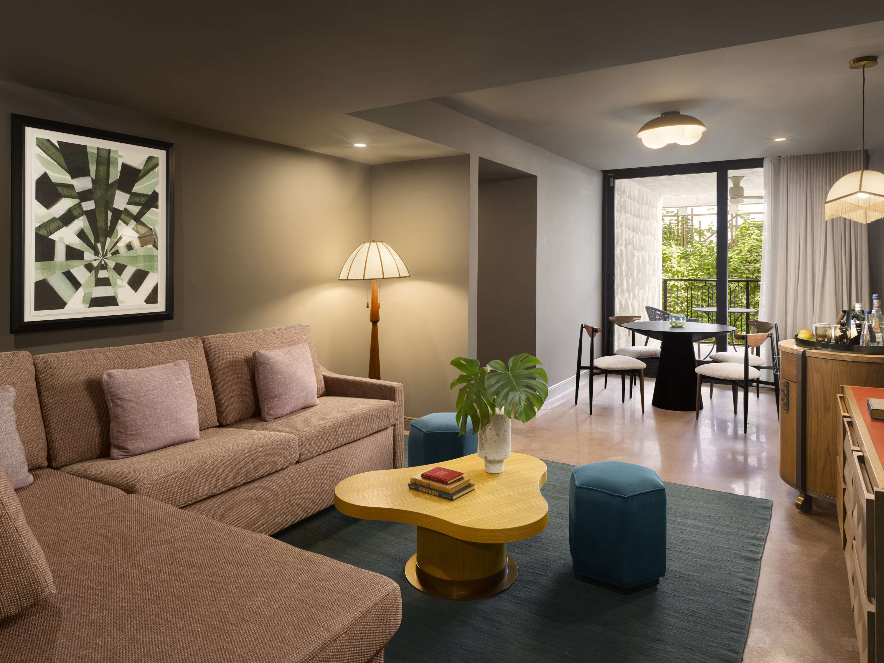 image Open-plan living and dining space with a blush sofa, scalloped yellow coffee table, and a balcony door framing the garden