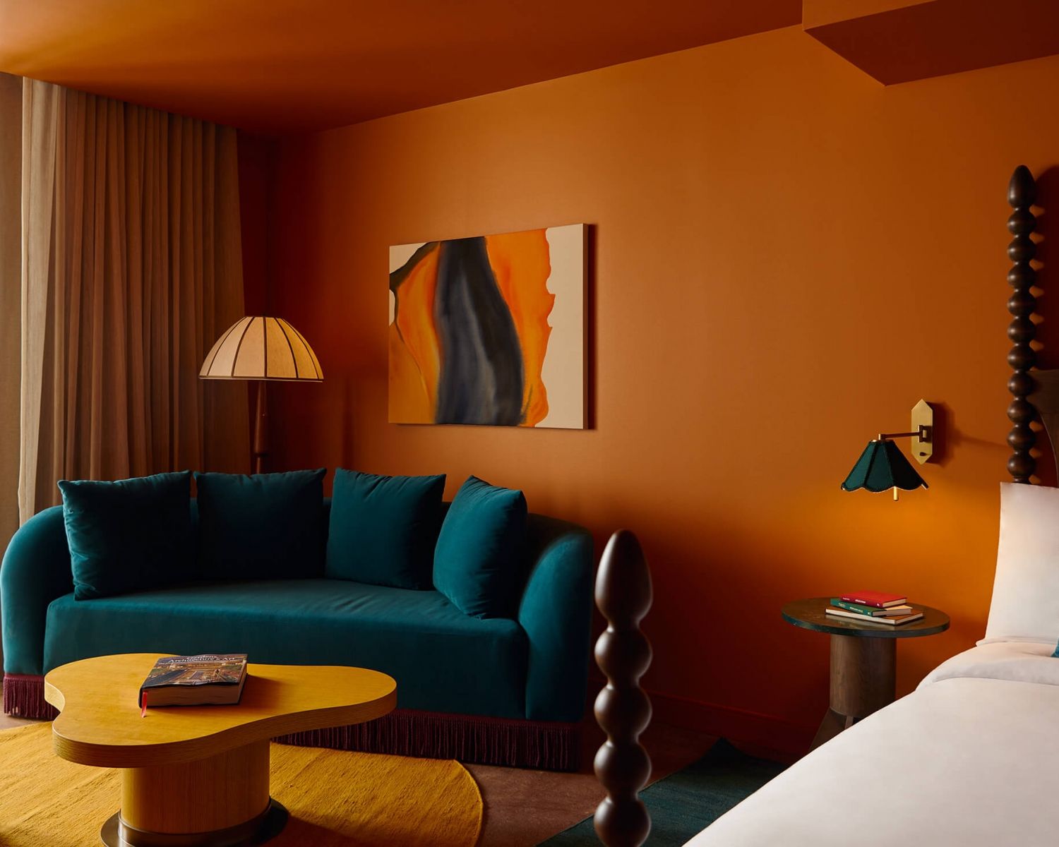 image Teal velvet sofa against terracotta-orange walls, organic yellow coffee table, and an abstract canvas — the living area