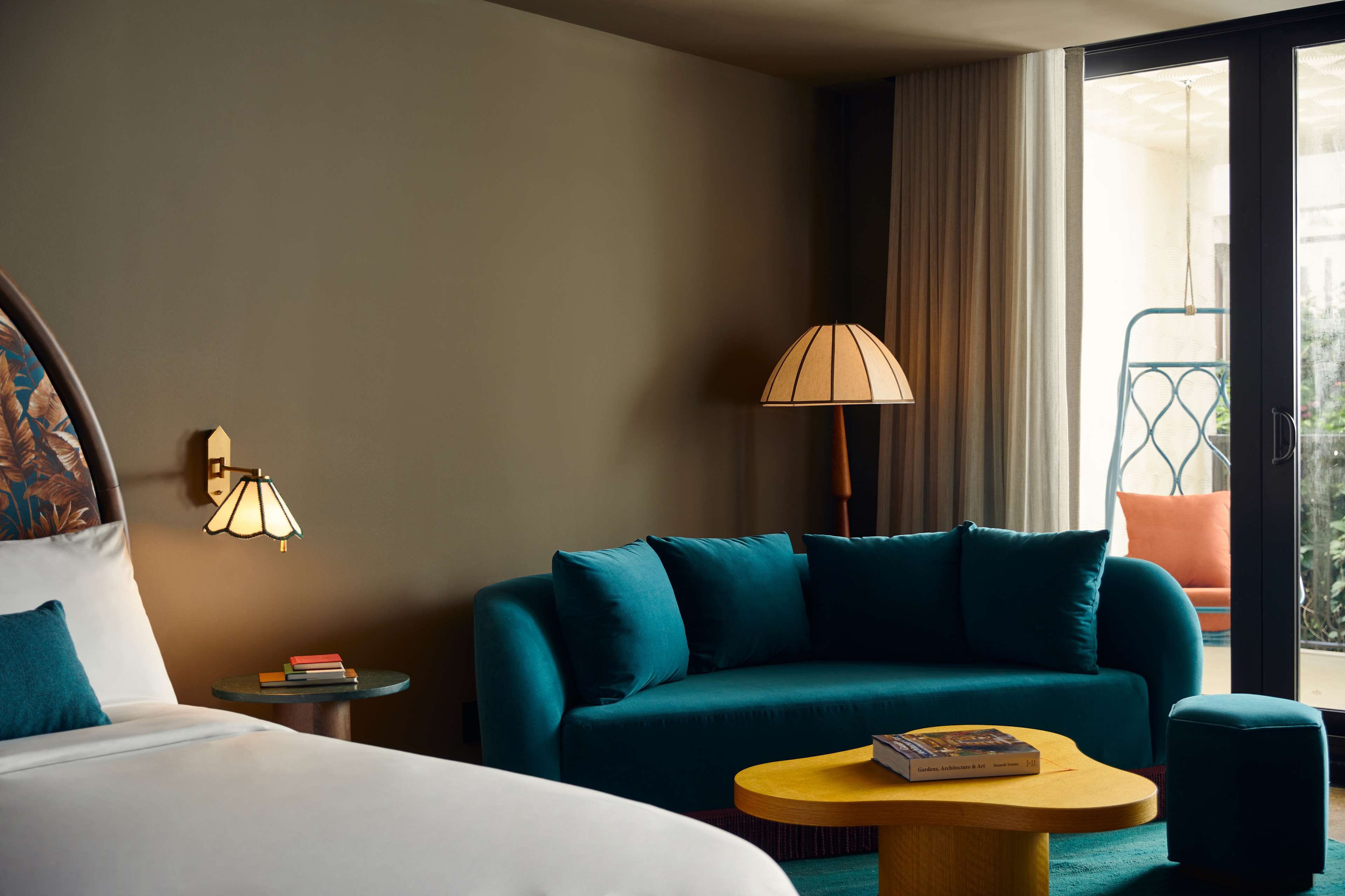 image Teal velvet sofa and organic yellow coffee table in the living nook, with a stained-glass wall sconce and balcony just beyond