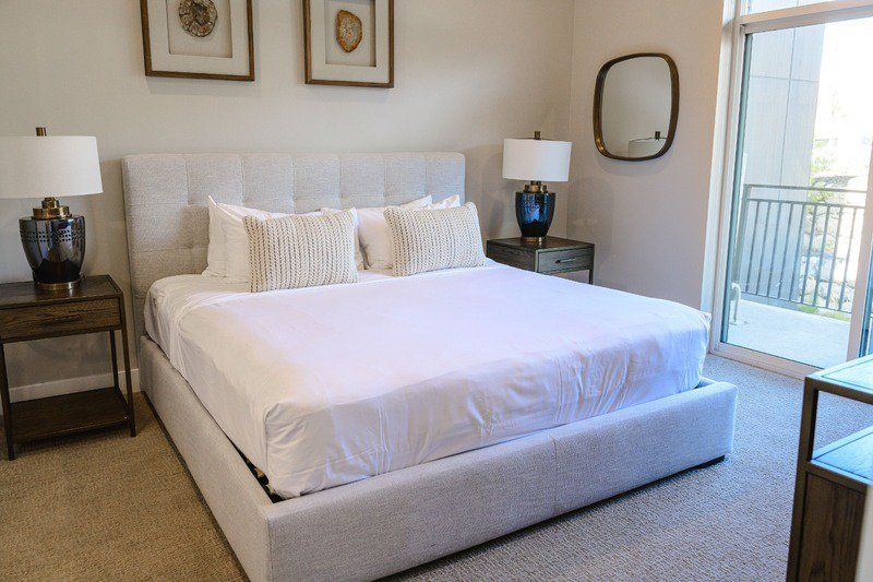 image King bed with tufted linen headboard, dual nightstands, and balcony access