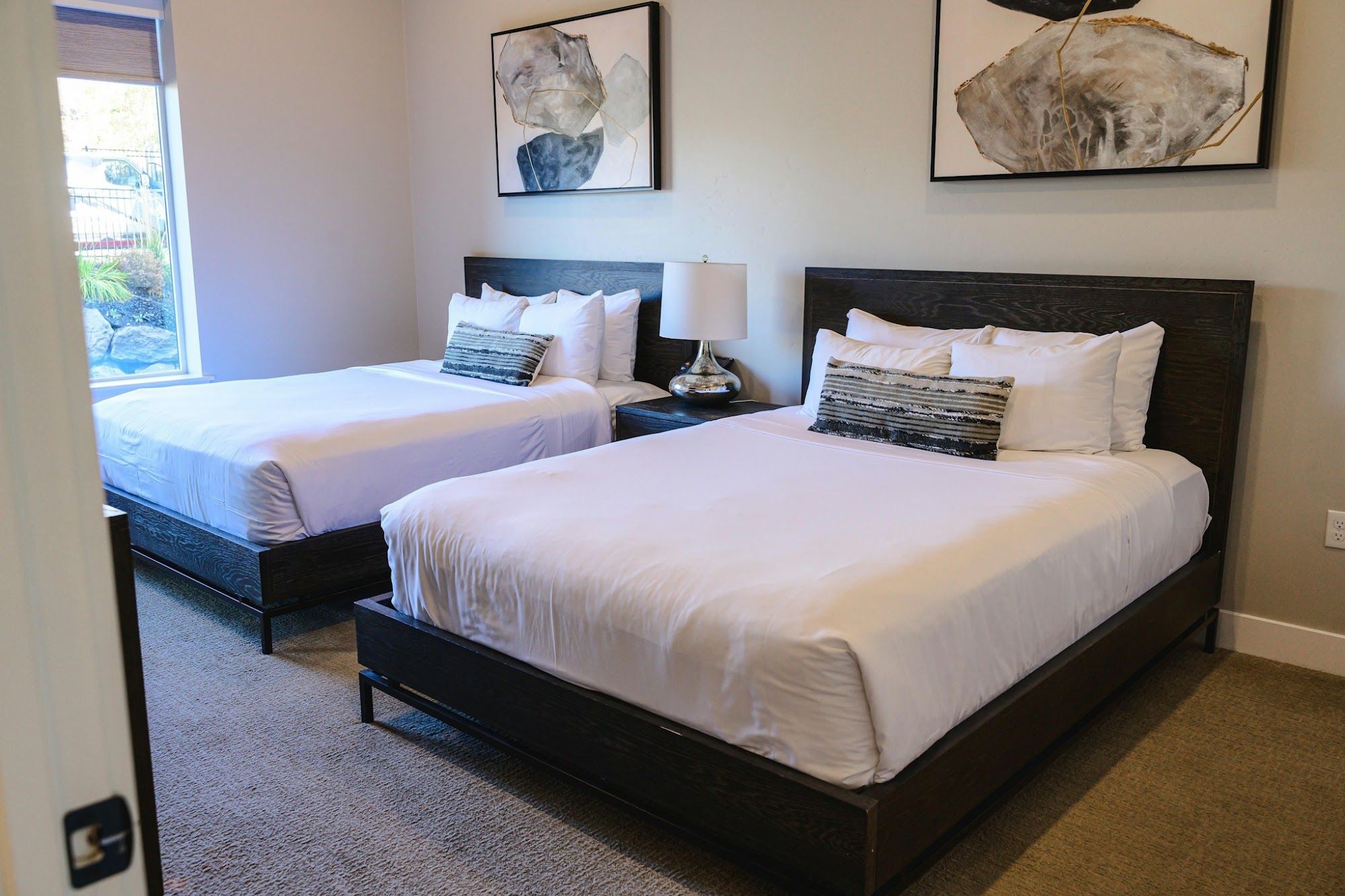 image Two queen beds with dark wood headboards and crisp white bedding
