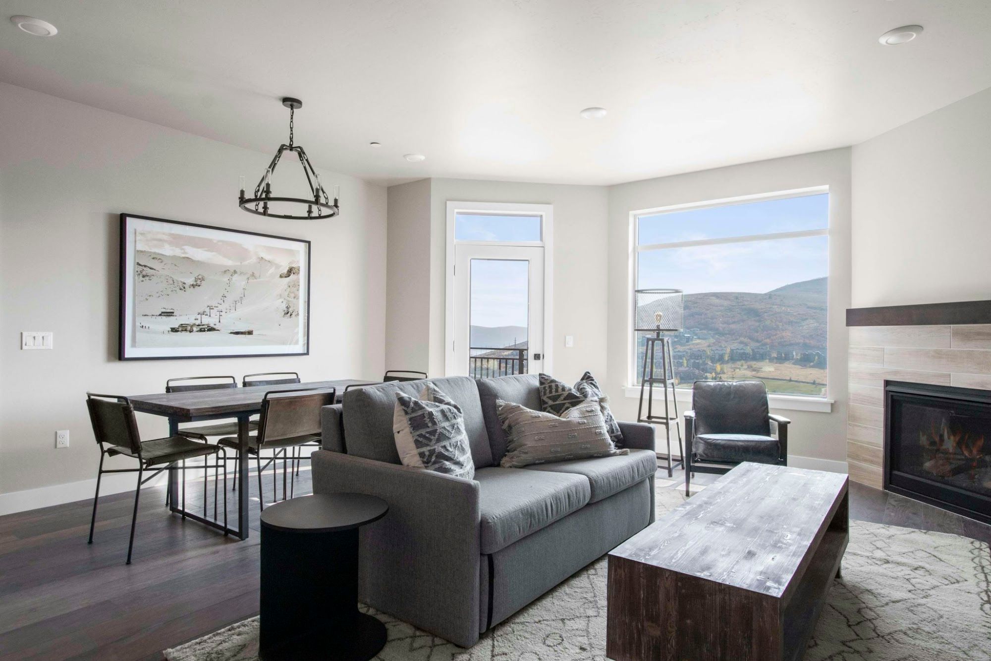image Bright living area with gray sofa, dining table, and mountain views