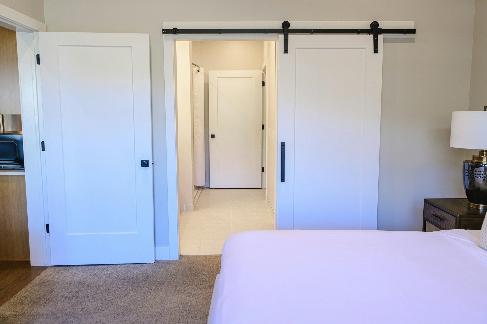 image Bedroom with sliding barn door opening to the accessible bathroom beyond