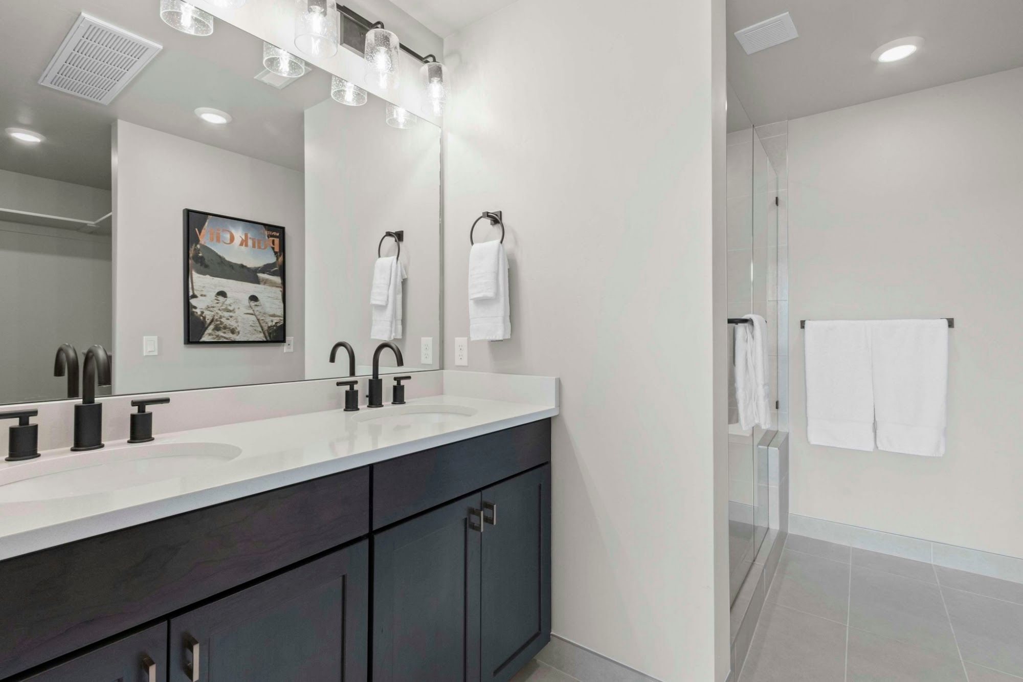 image Bathroom with double vanity, dual sinks, and glass walk-in shower
