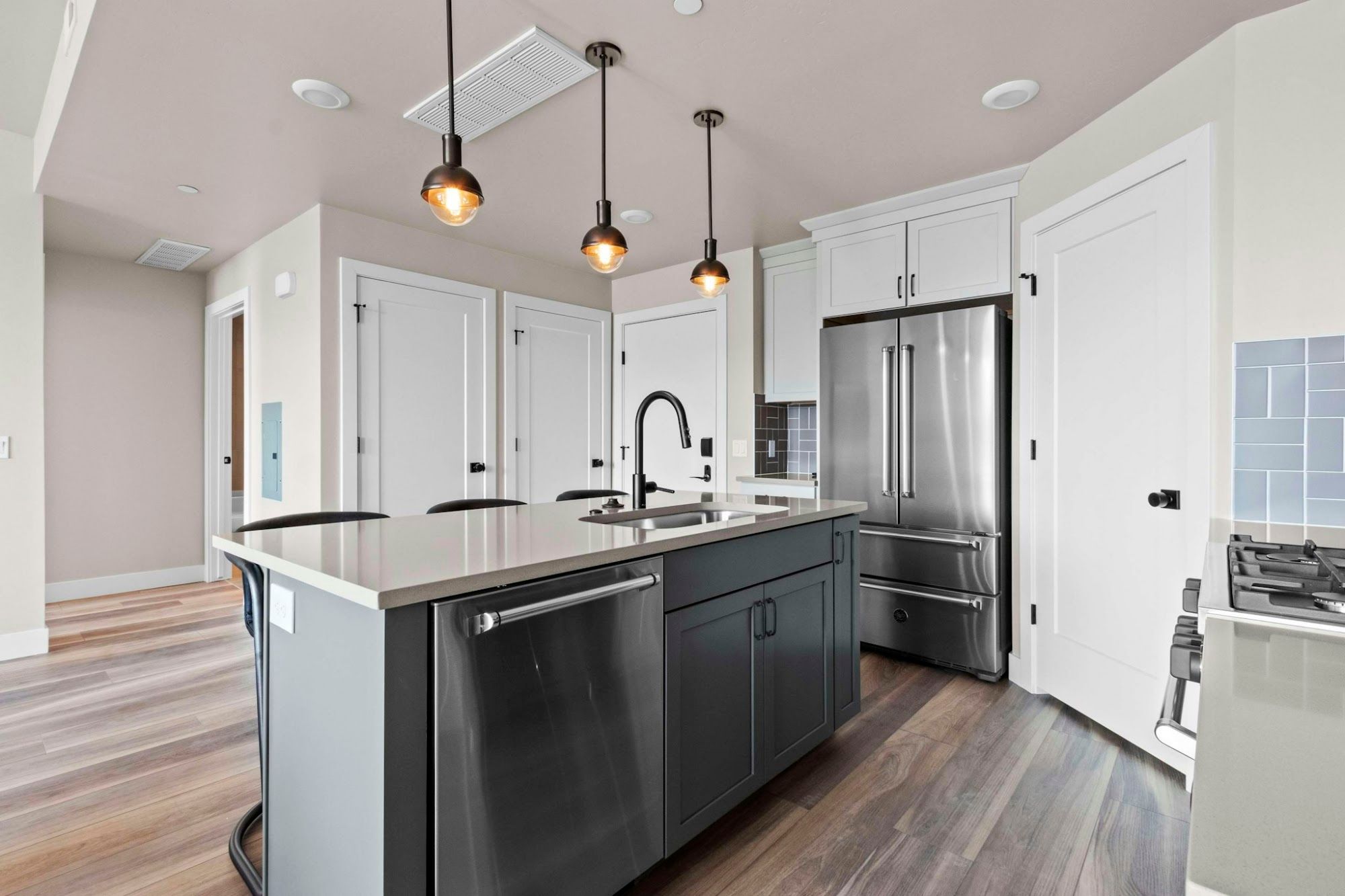 image Full kitchen with island, stainless steel French-door refrigerator, pendant lights, and hardwood floors