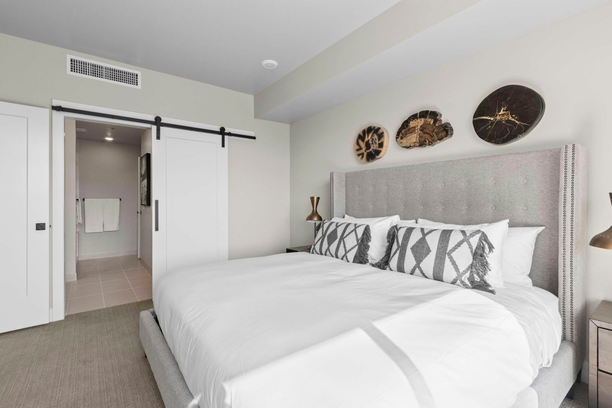 image King bed with tufted upholstered headboard and sliding barn door to ensuite bathroom