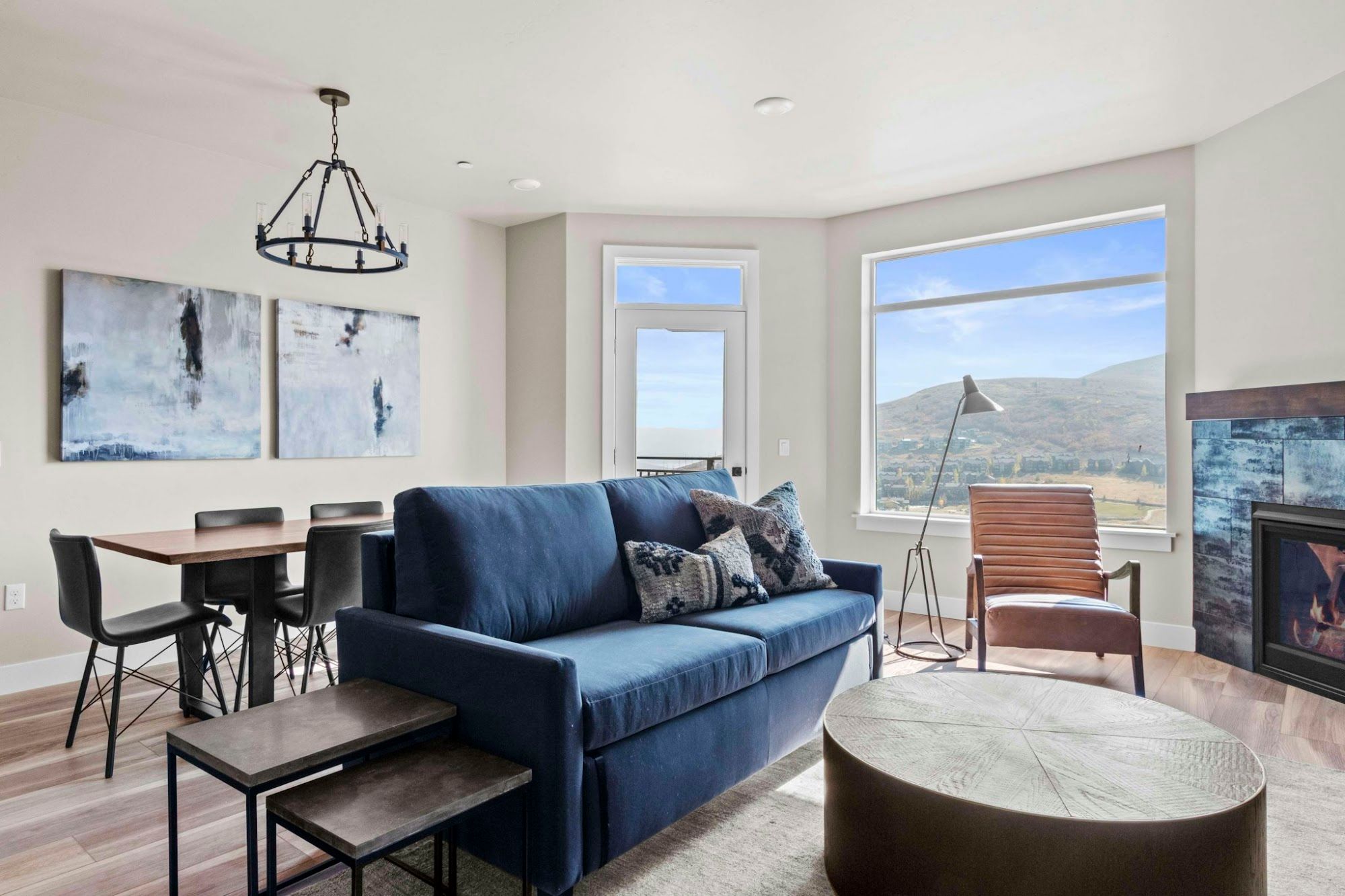 image Open living area with sofa sleeper, dining table, lit fireplace, and mountain views