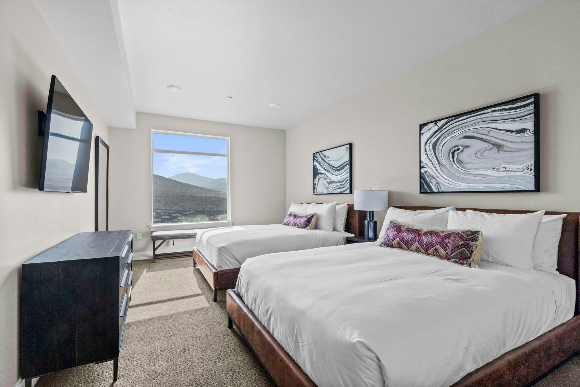 image Second bedroom with two queen beds, wall-mounted TV, and mountain view