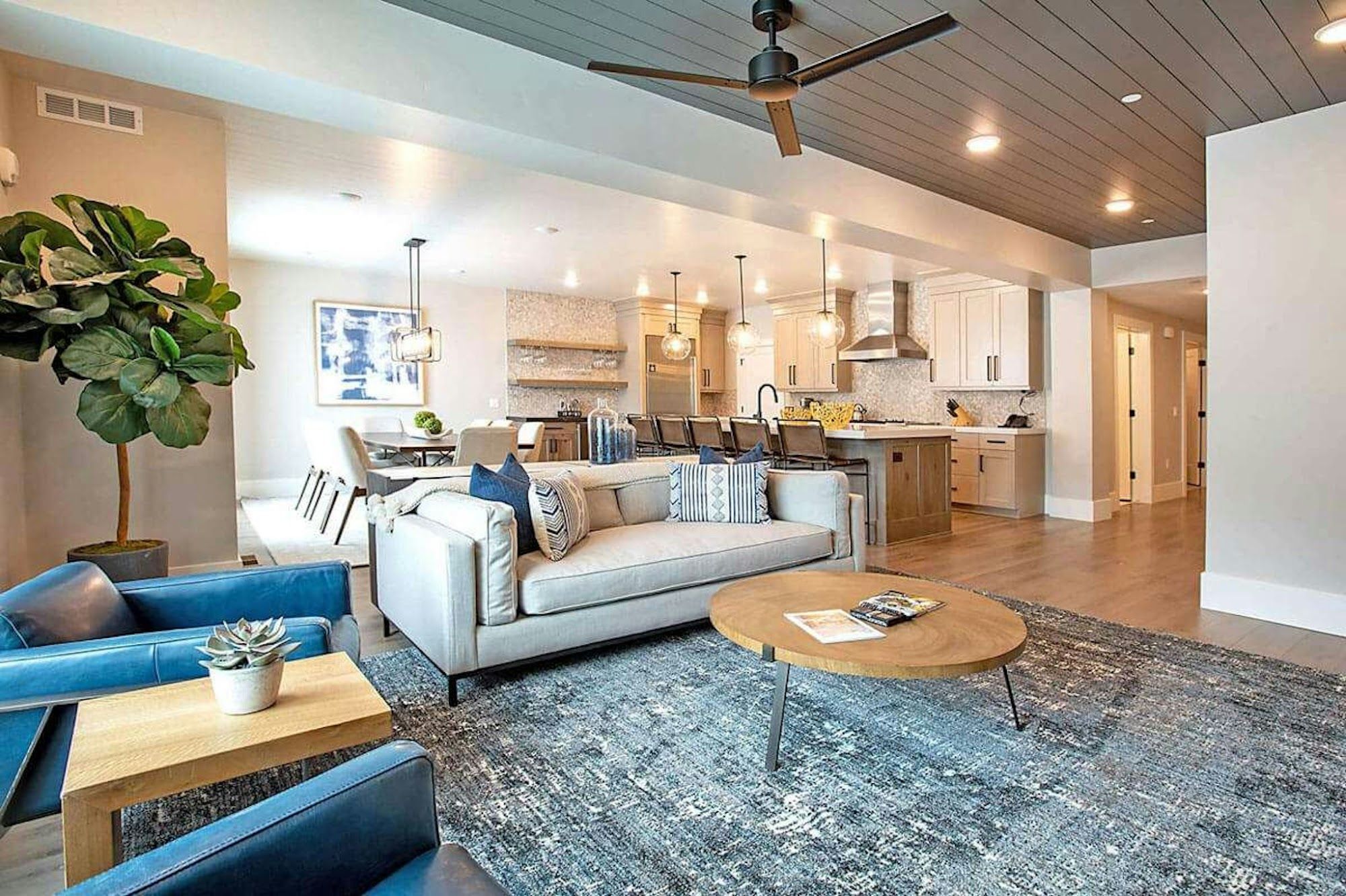 image Spacious open-plan living area with sectional sofa and blue leather chairs, open to full kitchen