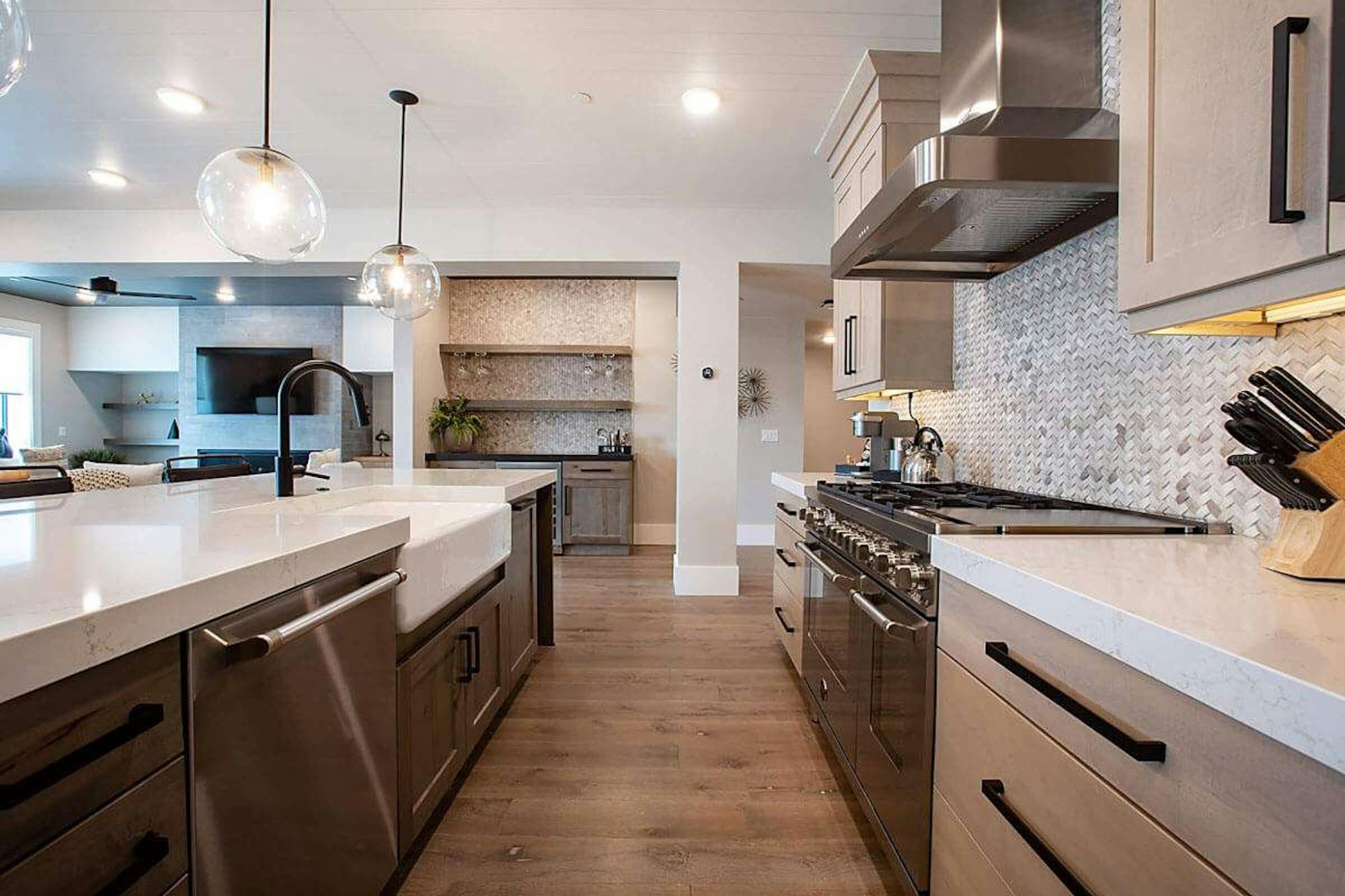 image Open-plan kitchen with large island, range hood, and bar alcove beyond