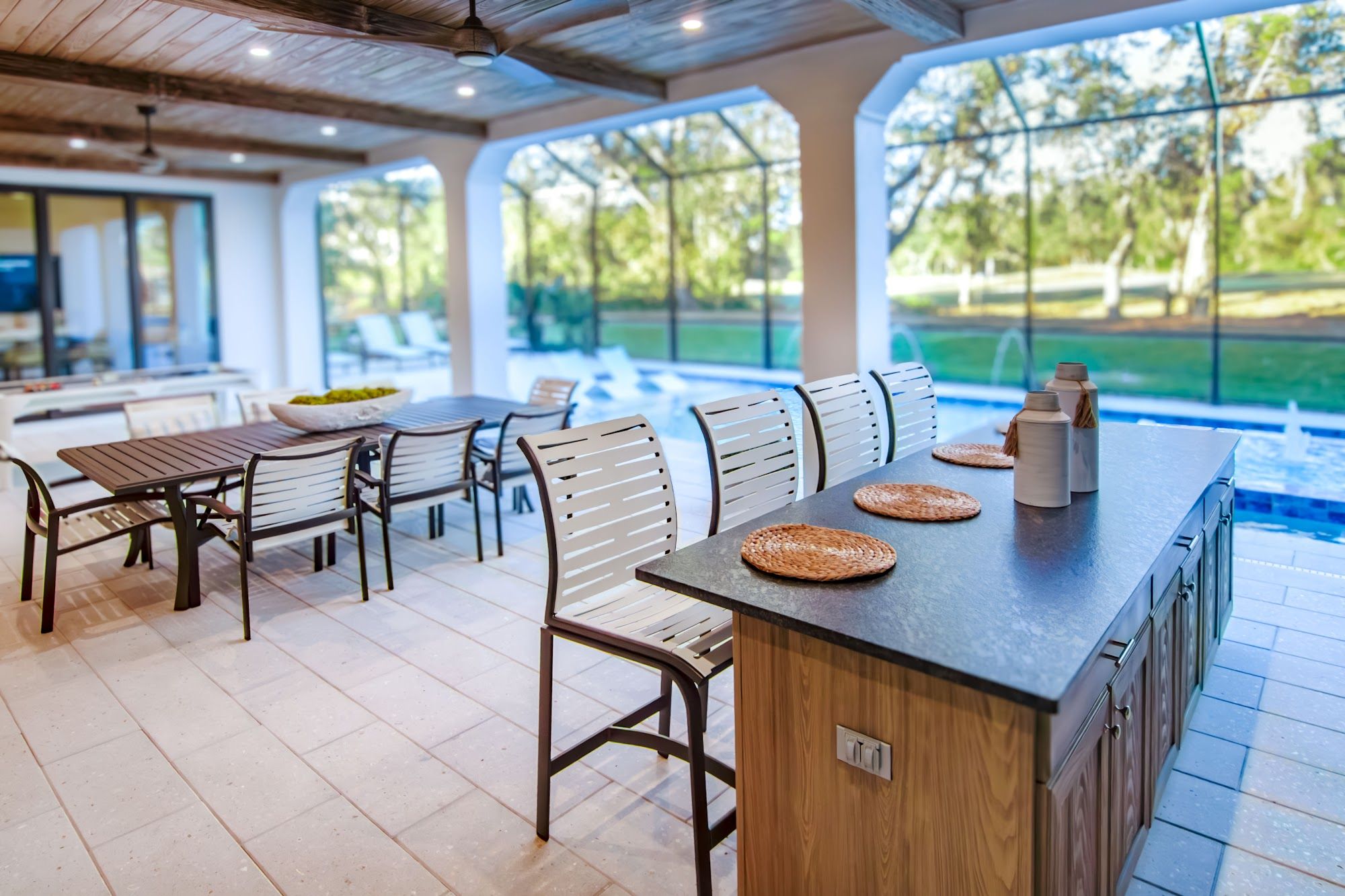 image Covered outdoor kitchen with bar seating overlooking pool area