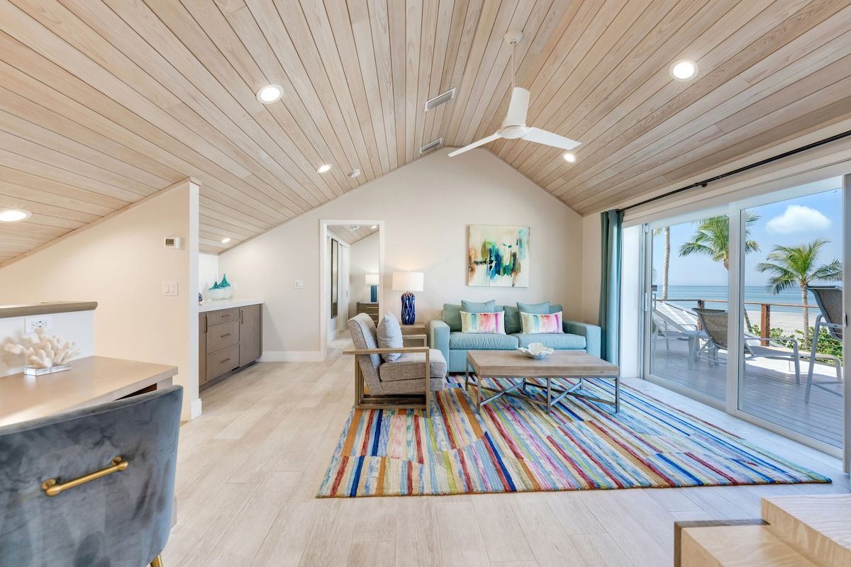 image The bright living area has vaulted wood ceilings, colorful décor, and sliding doors opening to a furnished ocean-view balcony.