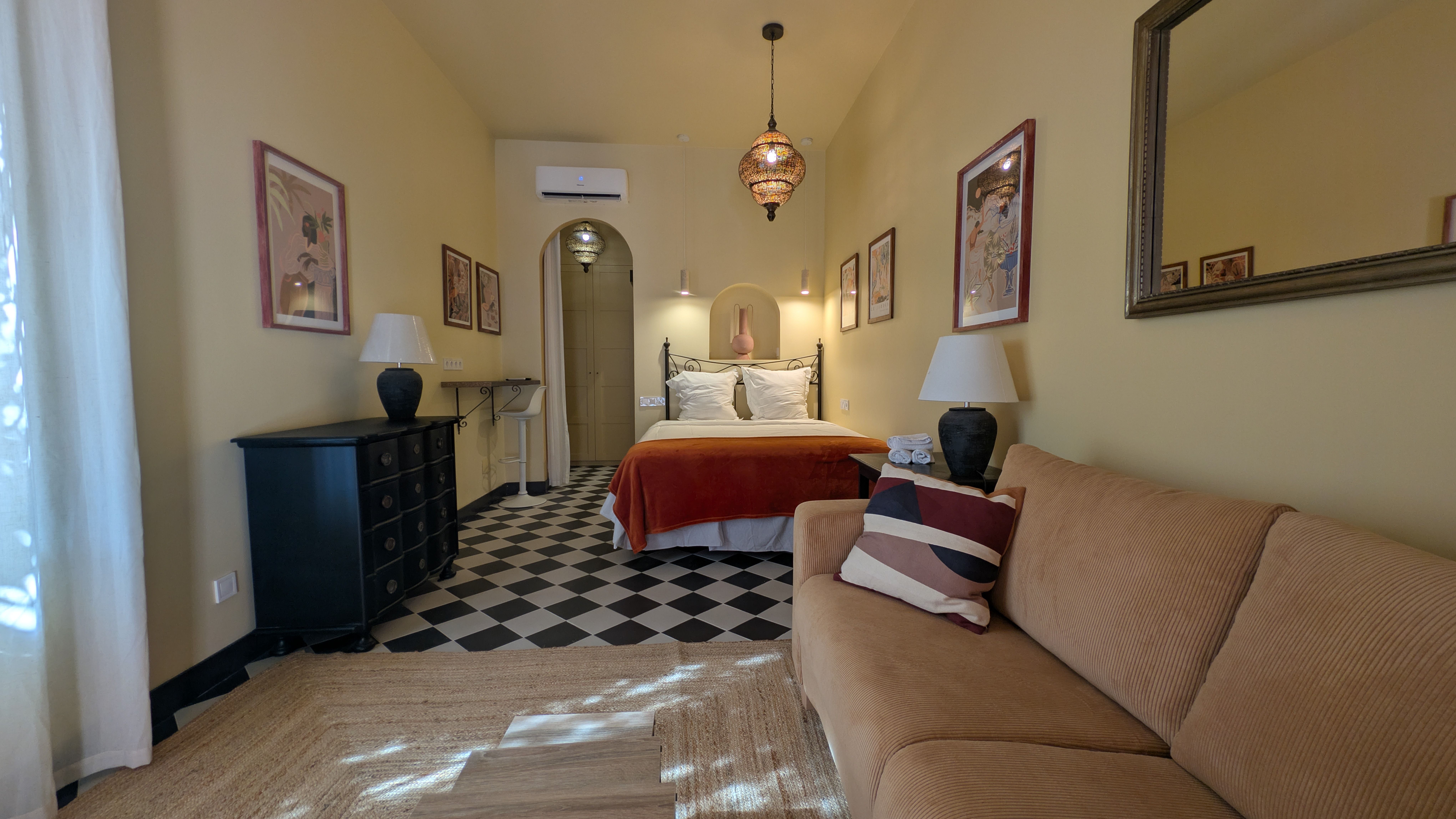 image Bright, open-plan room with a comfortable bed, sofa, air conditioning, and plenty of natural light.