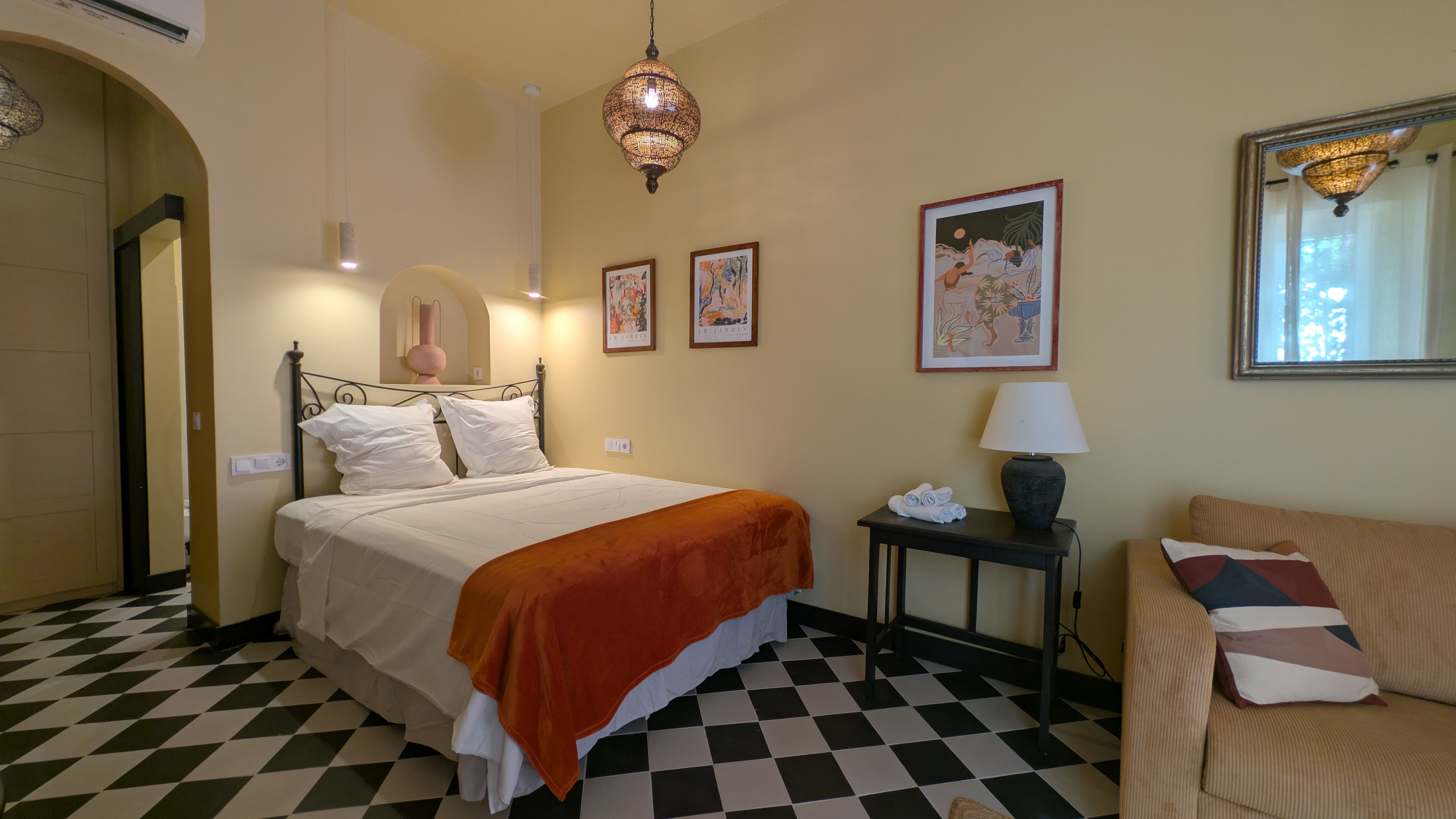 image Cozy sleeping area with a double bed, bedside tables, sofa, and charming decorative touches.