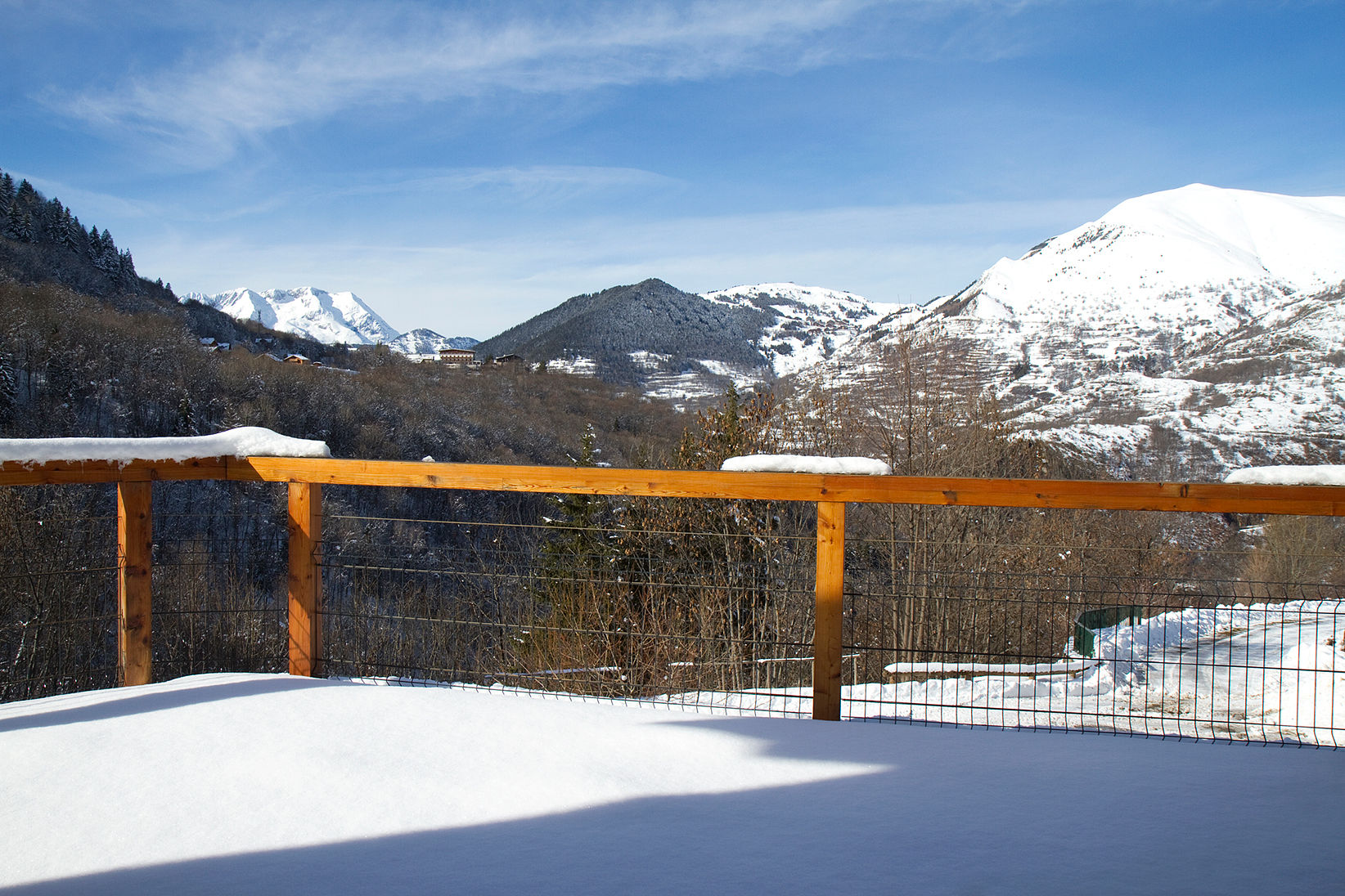 image Snow-covered terrace with wooden railing overlooking mountain scenery
