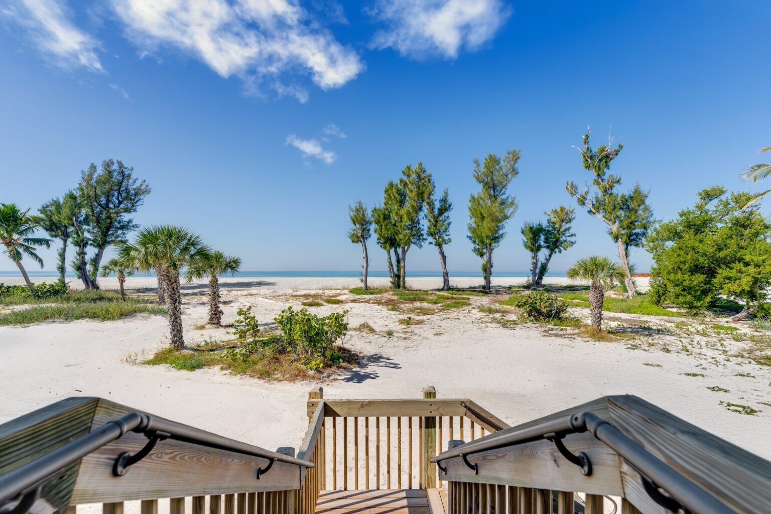 image Steps lead down to a tranquil beach, framed by swaying palms and a bright blue sky.