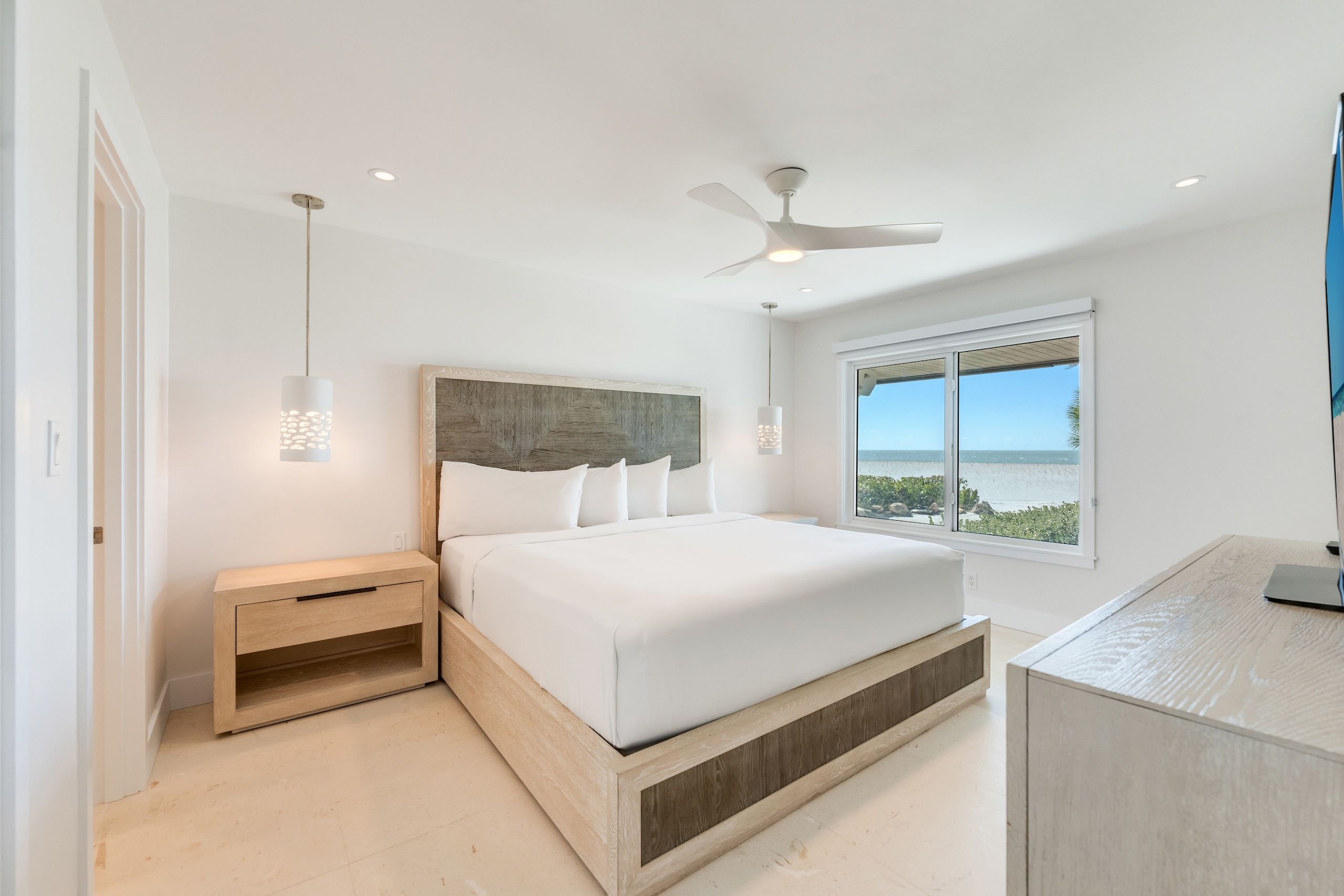 image The serene master bedroom features a tranquil seaside vista framed by large windows.