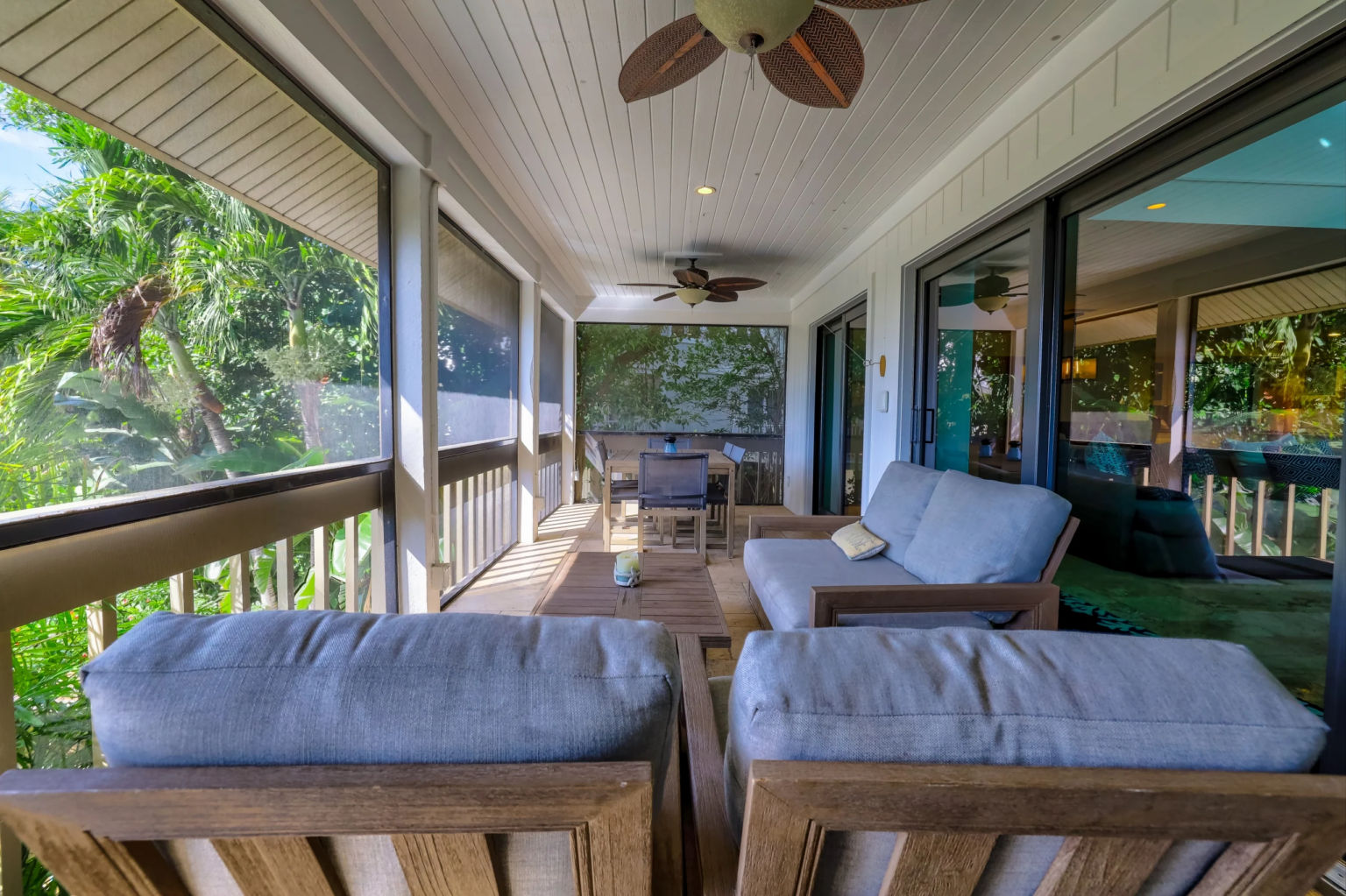 image Sunlight streams through the screens, illuminating the cozy seating on the private porch surrounded by lush greenery.