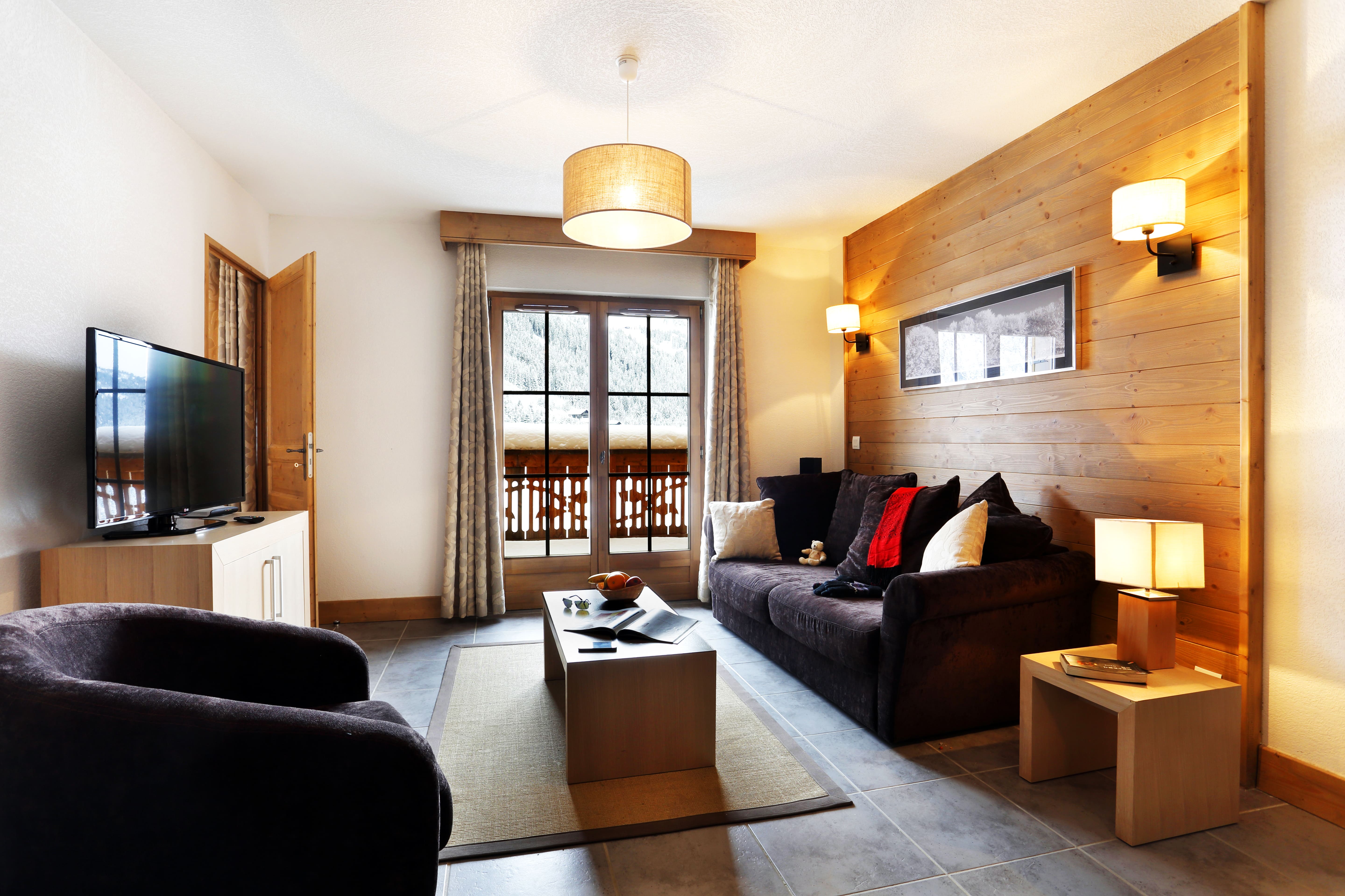 image The wood-clad living room opens onto a snow-topped balcony, with a flat-screen TV opposite the sofa.
