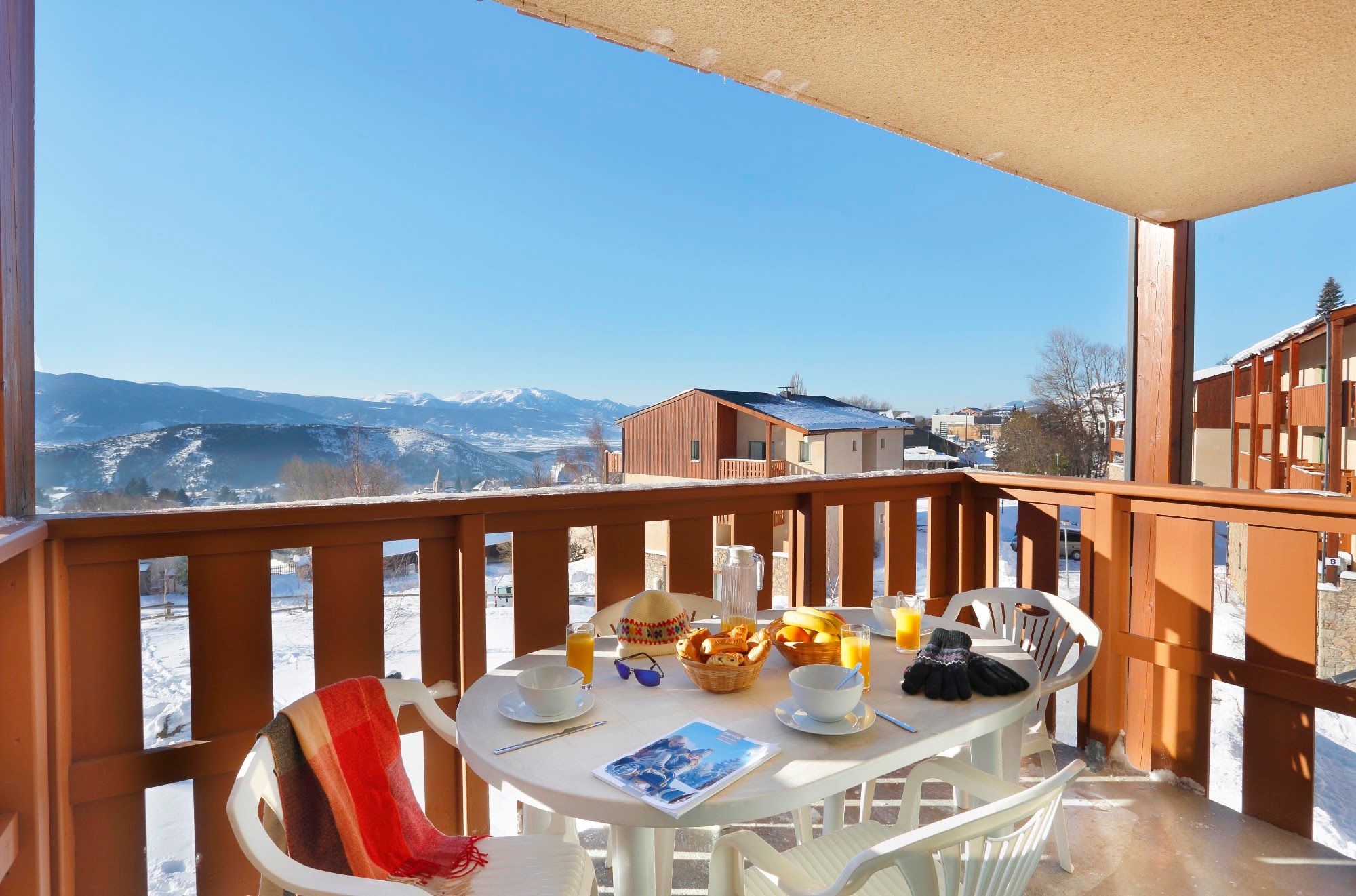 image Private balcony with table and four chairs overlooking snowy rooftops