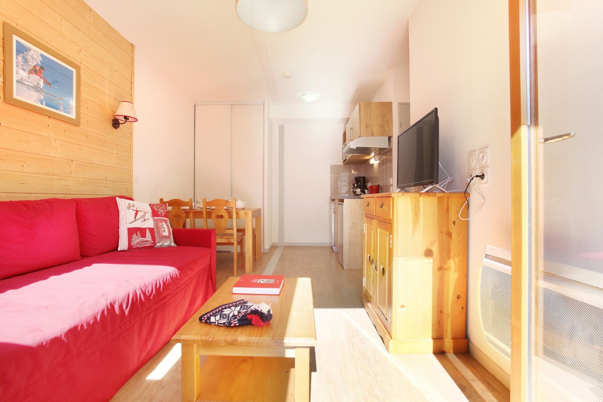 image Bright living area with a red sofa and open kitchenette