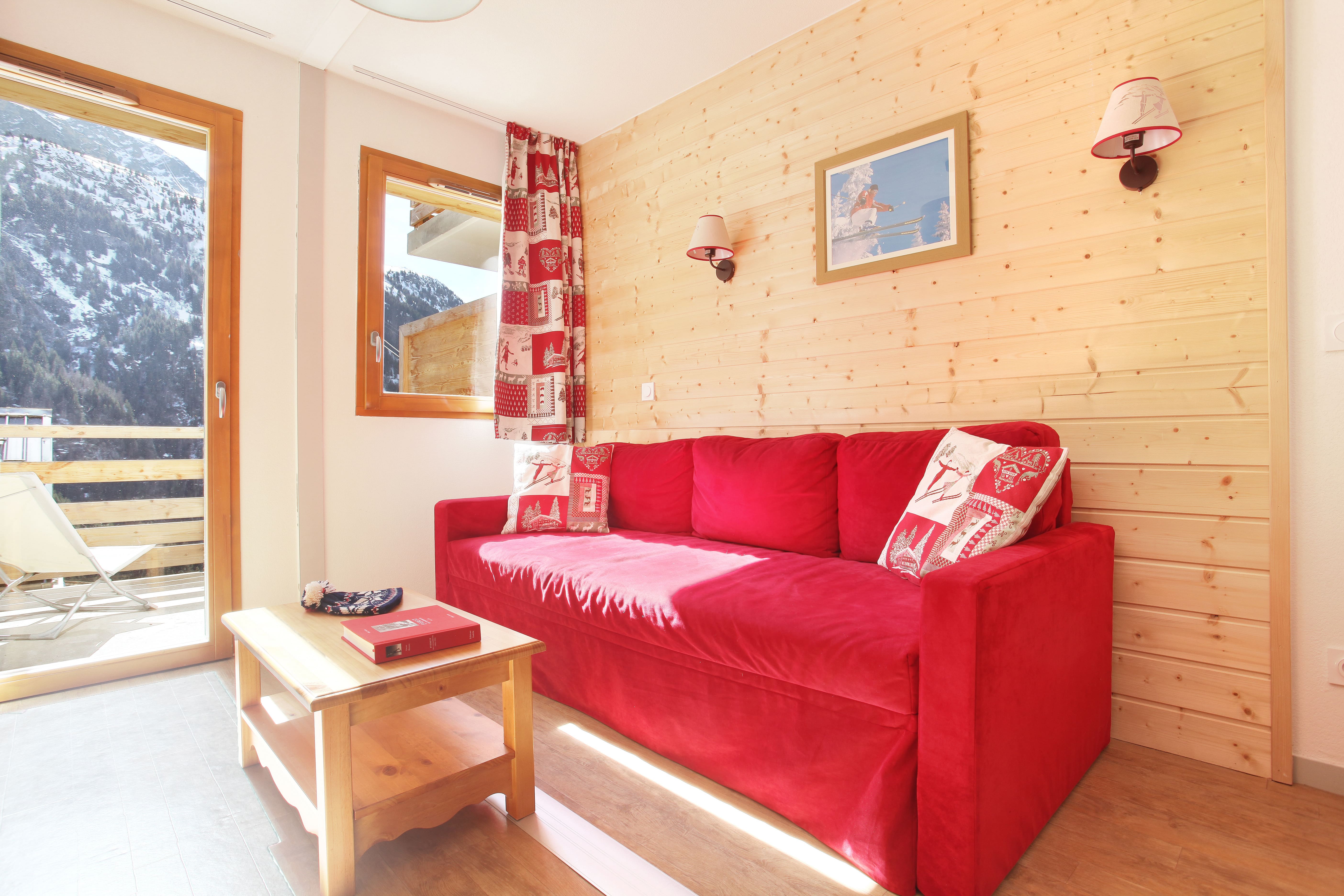 image Natural light floods the room, catching the red couch after a day of skiing
