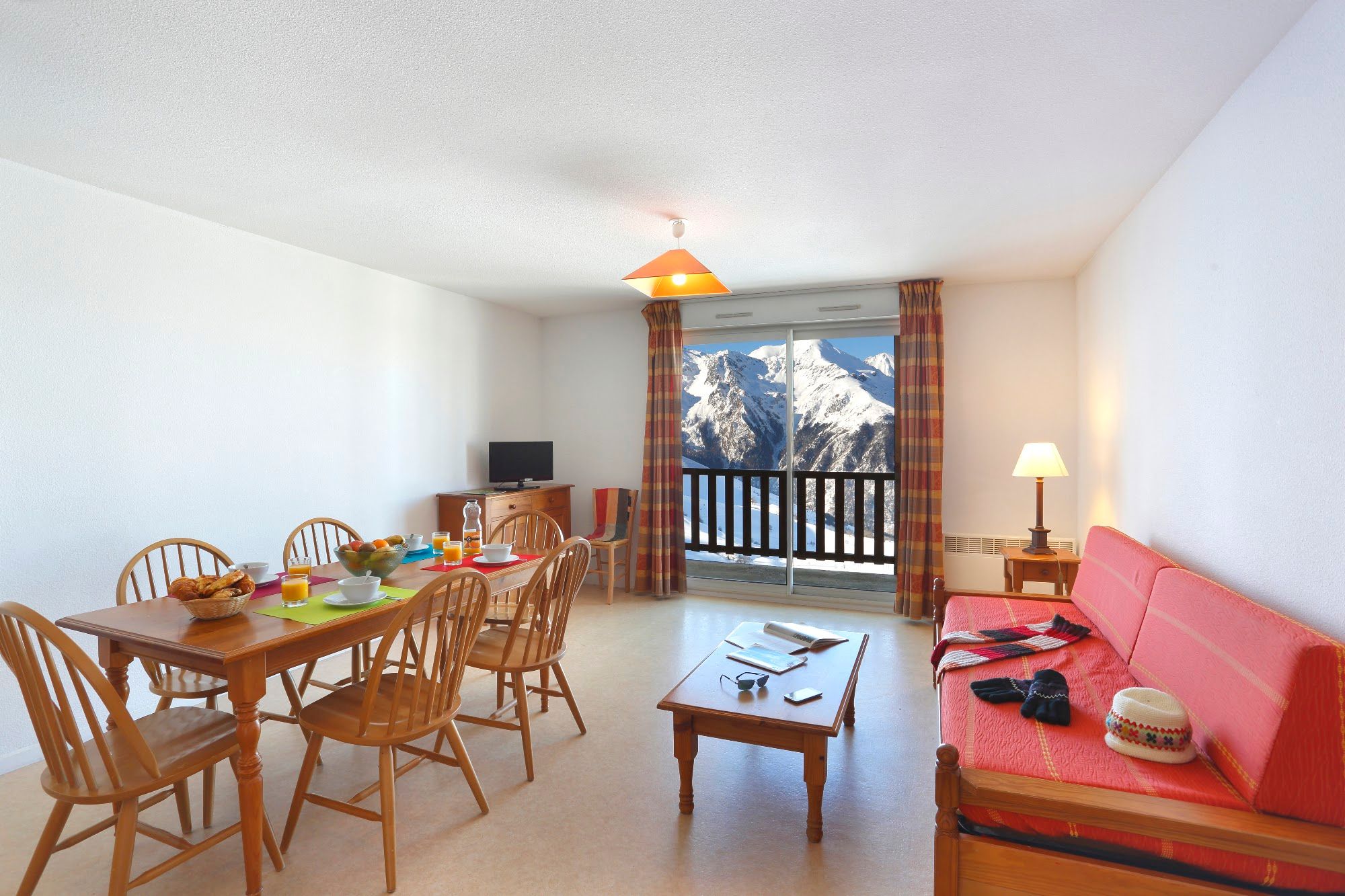 image Open-plan living and dining area with sliding doors onto a balcony and a snow-covered mountain view