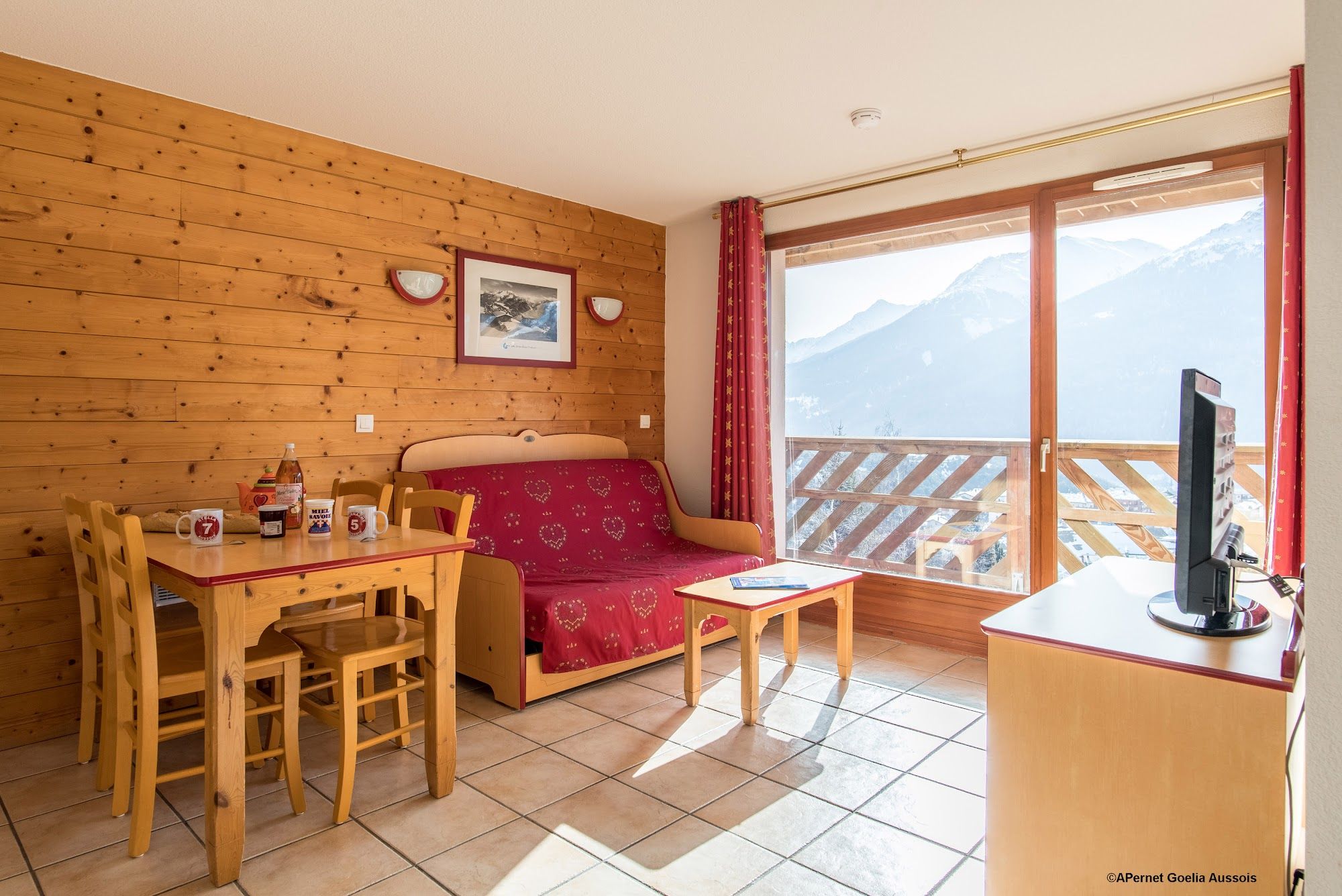 image Sitting and dining area with sofa bed, TV and balcony doors to a mountain view