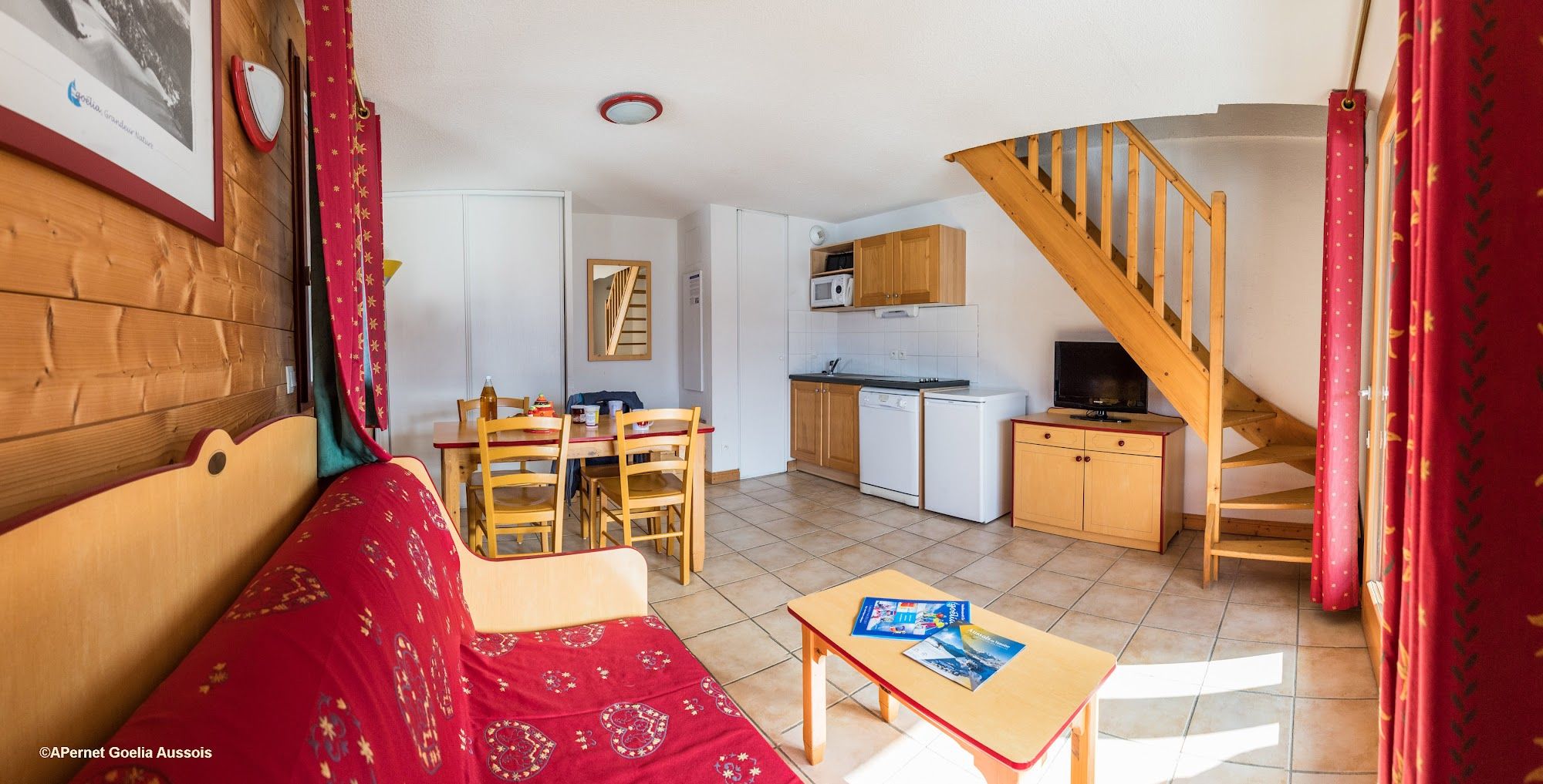 image Living area with red sofa bed, kitchenette and stairs to the upper floor